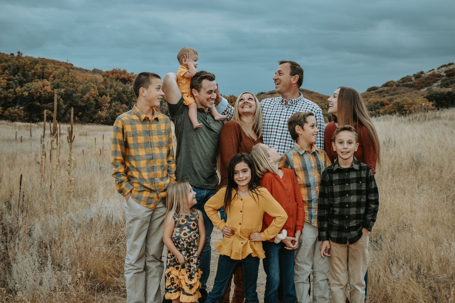 Large extended family group portrait in an autumn golden grass meadow landscape.