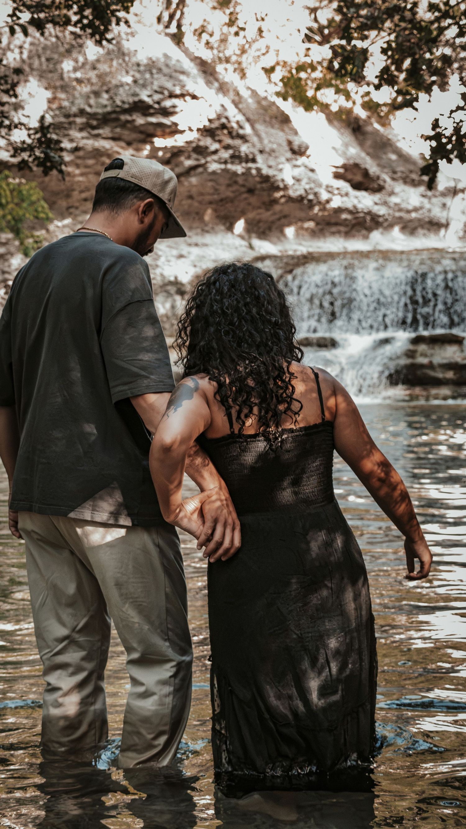 Couple standing in shallow water near a waterfall for a couples session.