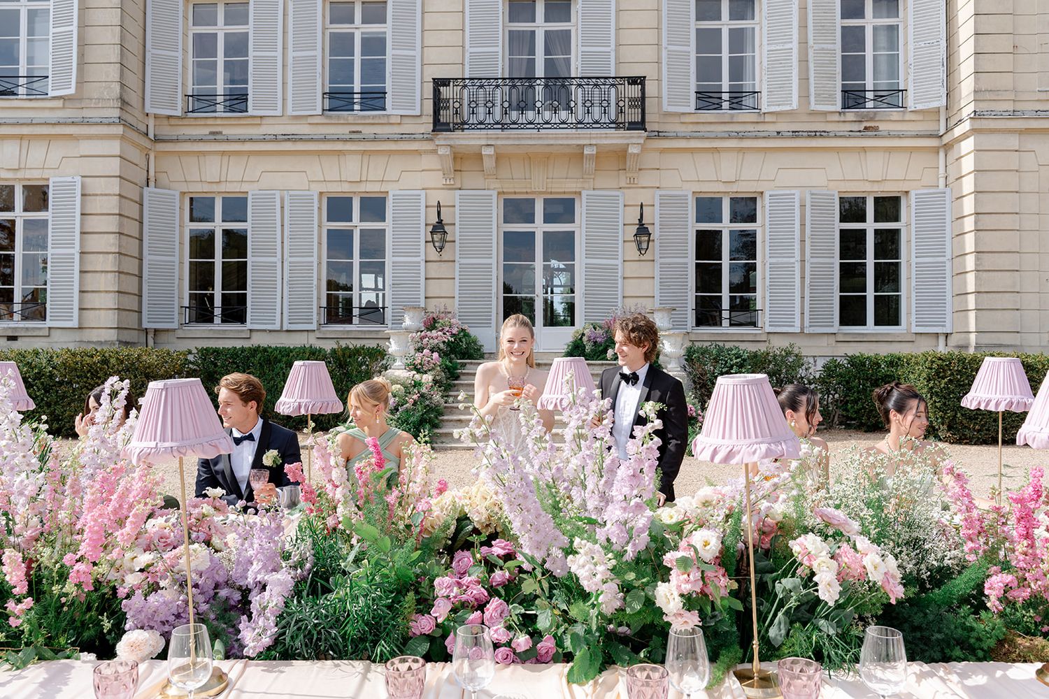 Wedding reception at French chateau with lush pink floral arrangements and romantic table setting.