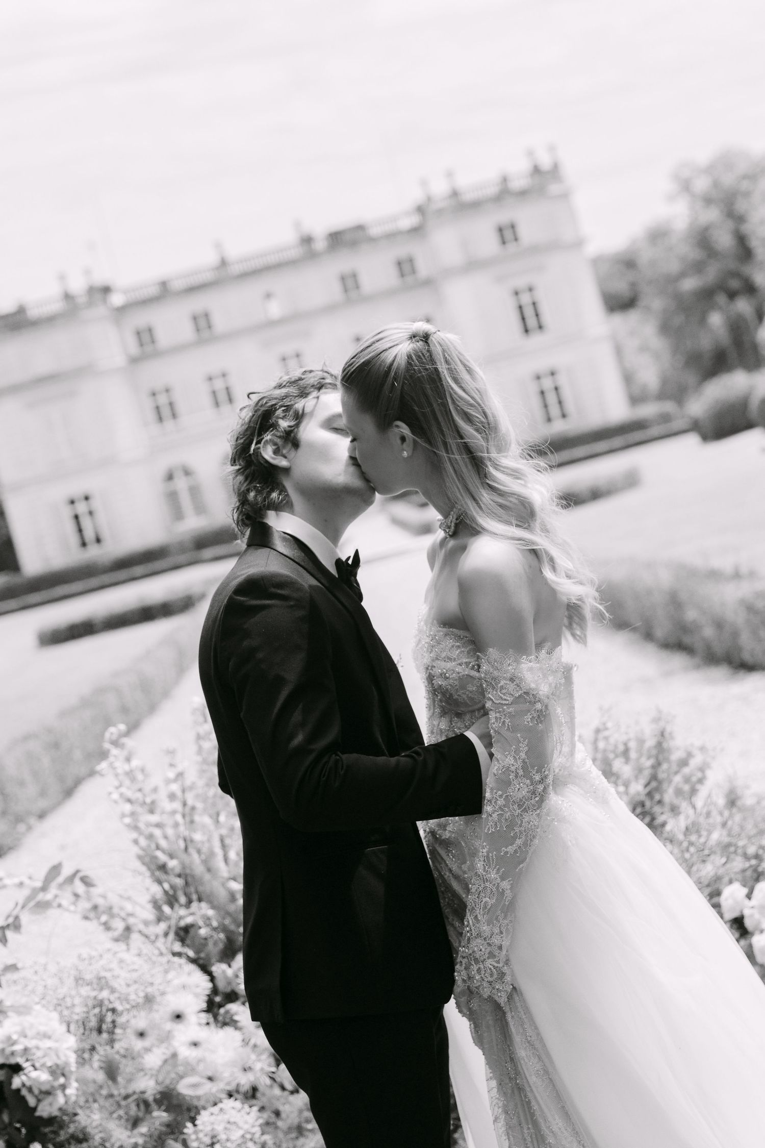Black and white photo of bride and groom sharing a kiss in chateau garden.