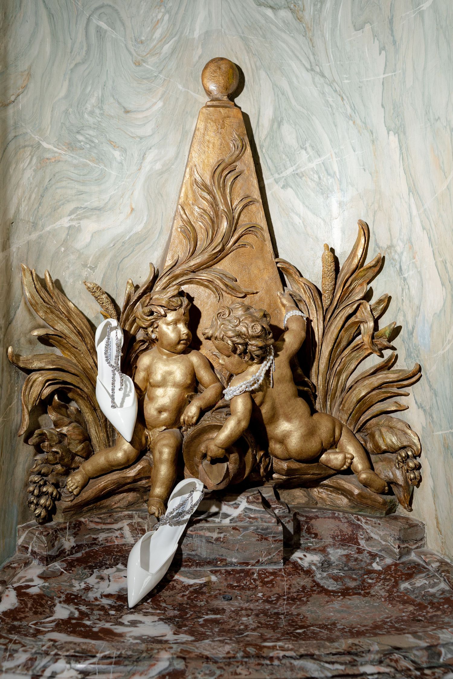 Golden baroque cherub sculpture with ornate acanthus leaves on marble pedestal, classical decorative art.
