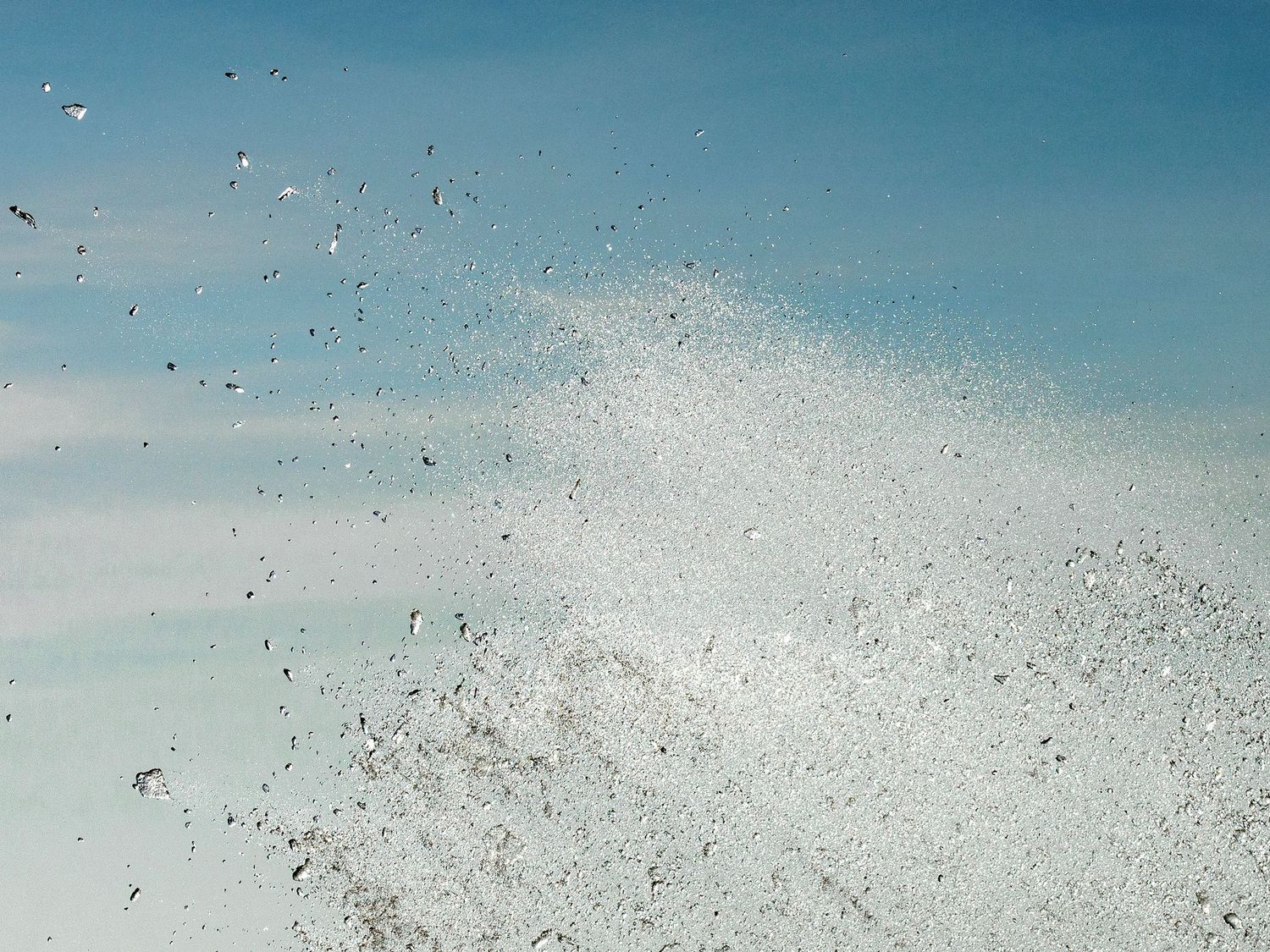 Aerial view of seagulls swarming over a white sandy beach meeting turquoise ocean waters.