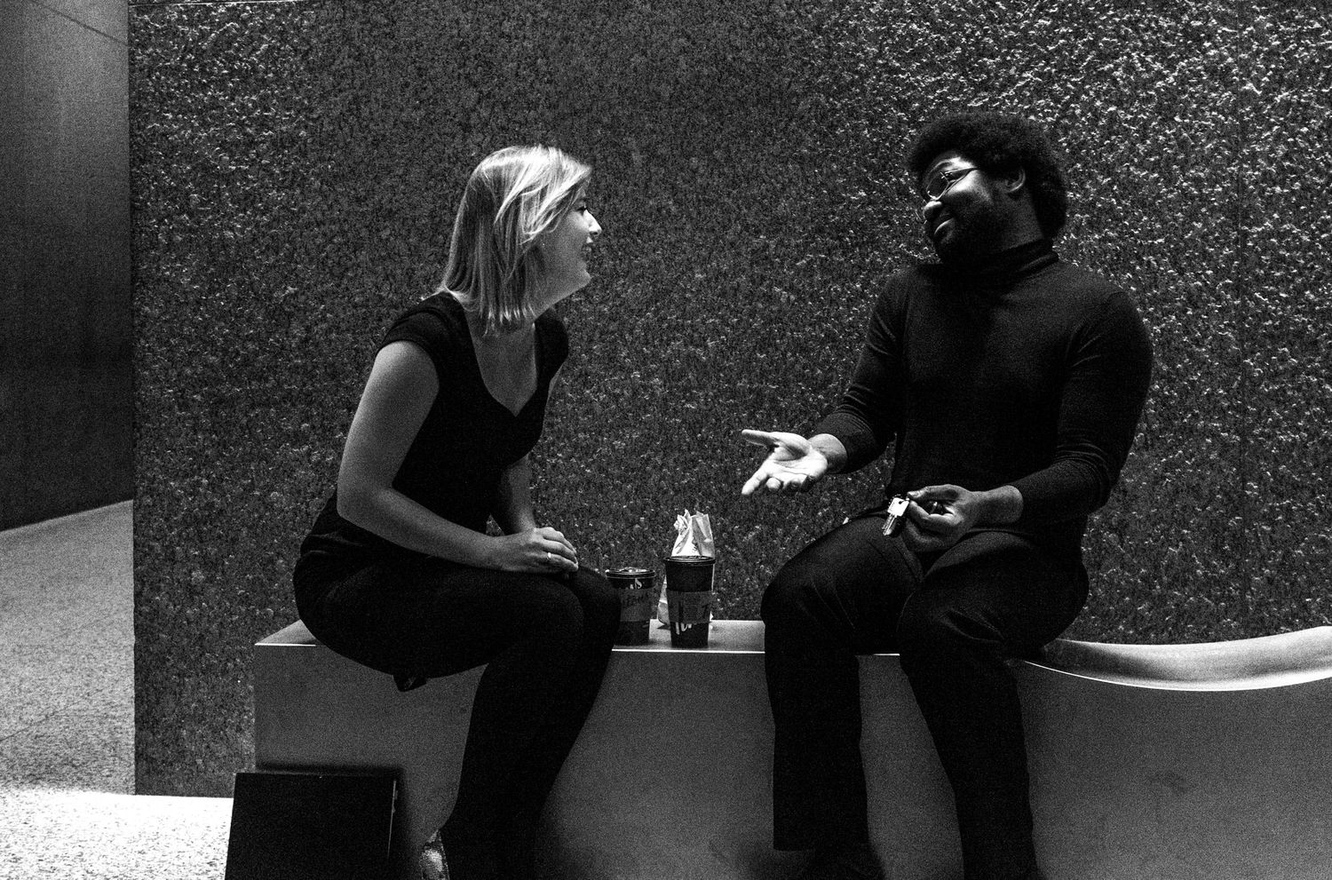Black and white photo of a man and woman in deep conversation while seated in an urban setting.