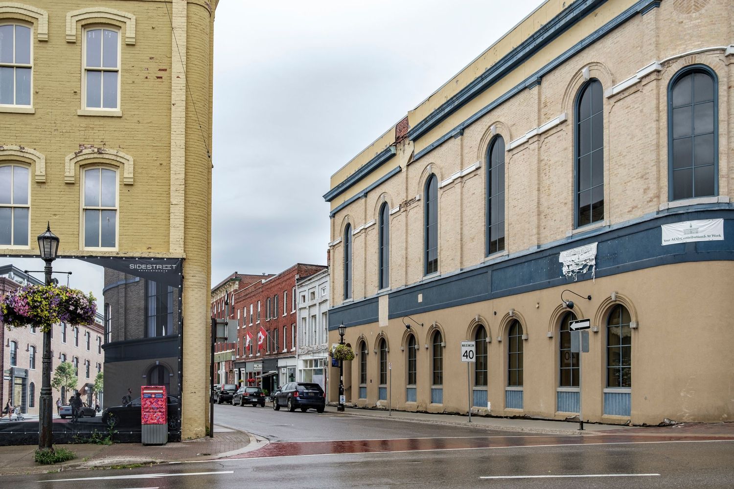 Historic downtown street corner with arched windows and colorful storefronts on a rainy day.