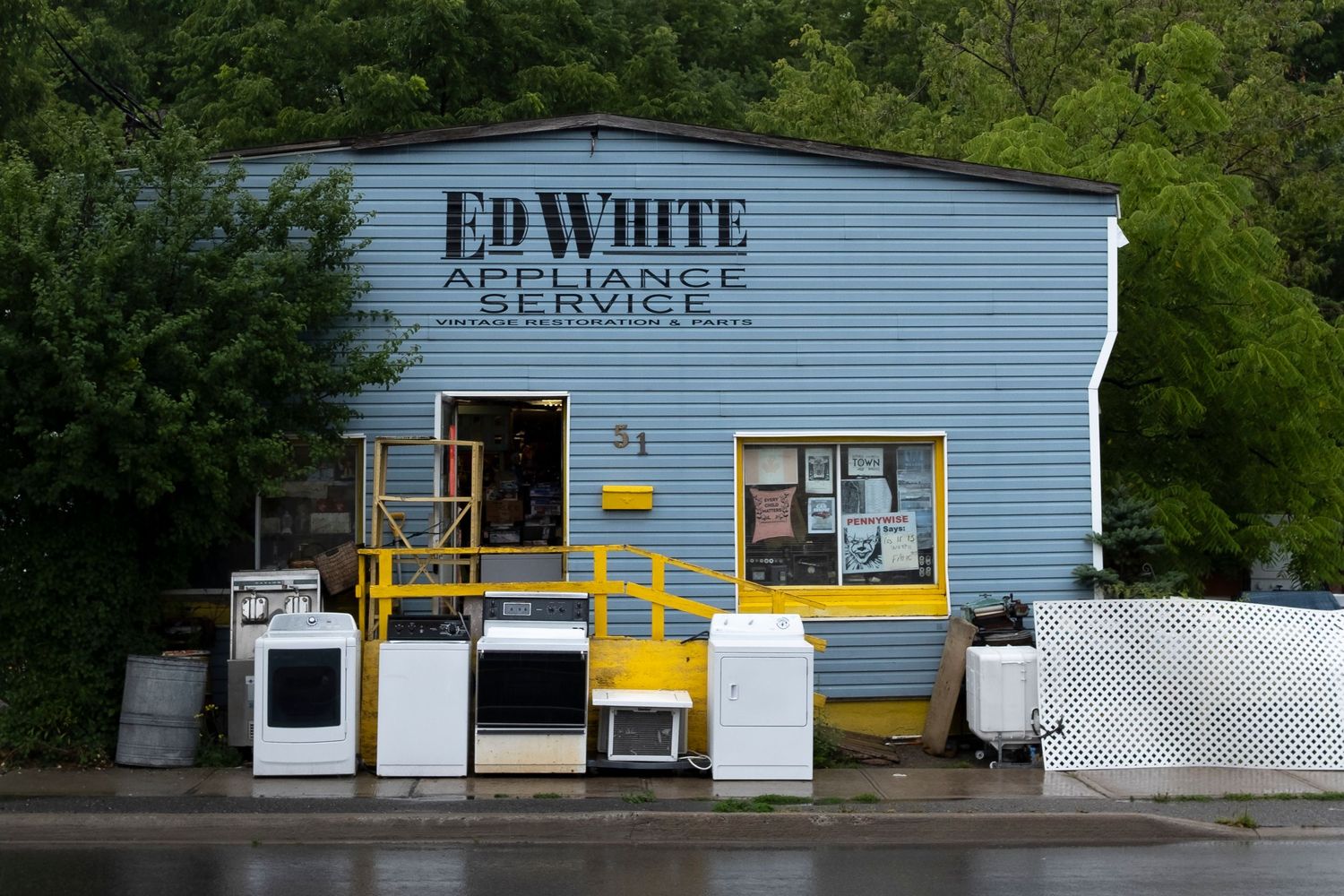 Ed White Appliance Service repair shop exterior with washers and dryers displayed outside on a rainy day.