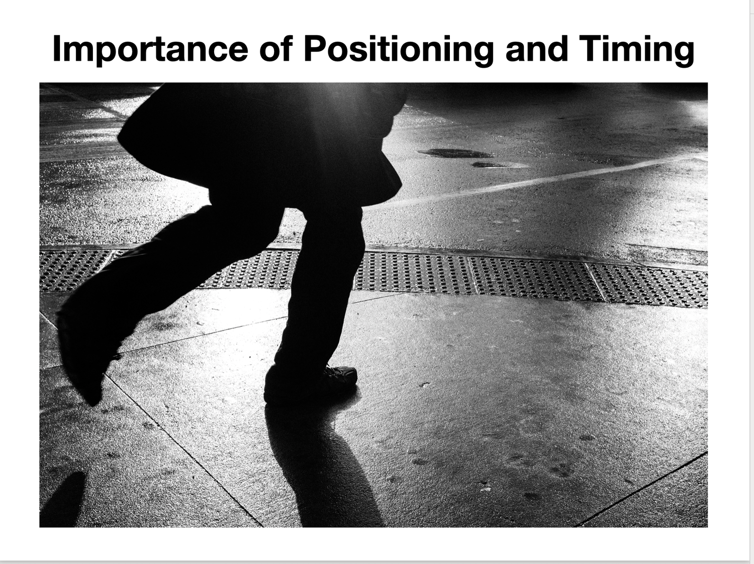 Black and white street photo showing dramatic shadows of a walking pedestrian on wet urban pavement.