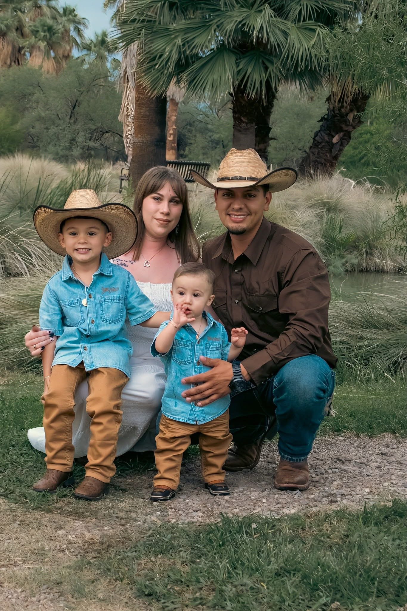 Family of four in cowboy hats posing outdoors near palm trees and greenery in coordinating outfits.