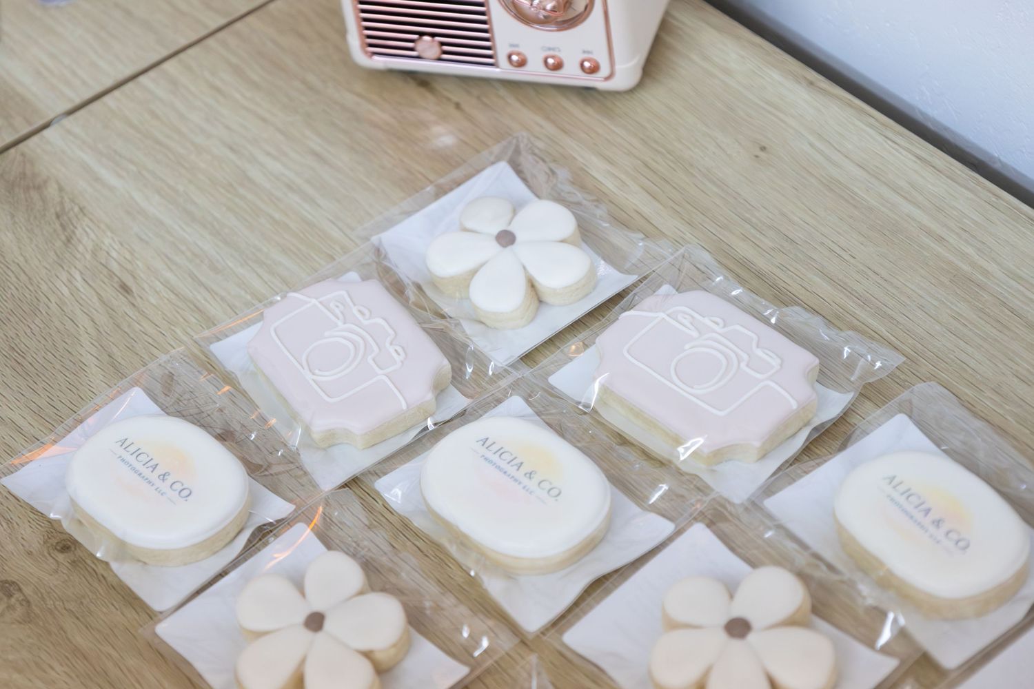 Seven individually wrapped white soaps with floral and camera designs arranged on wooden surface.