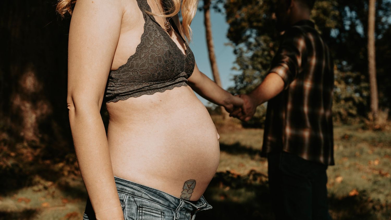 Maternity photo of expectant mother showing her baby bump in natural outdoor setting.