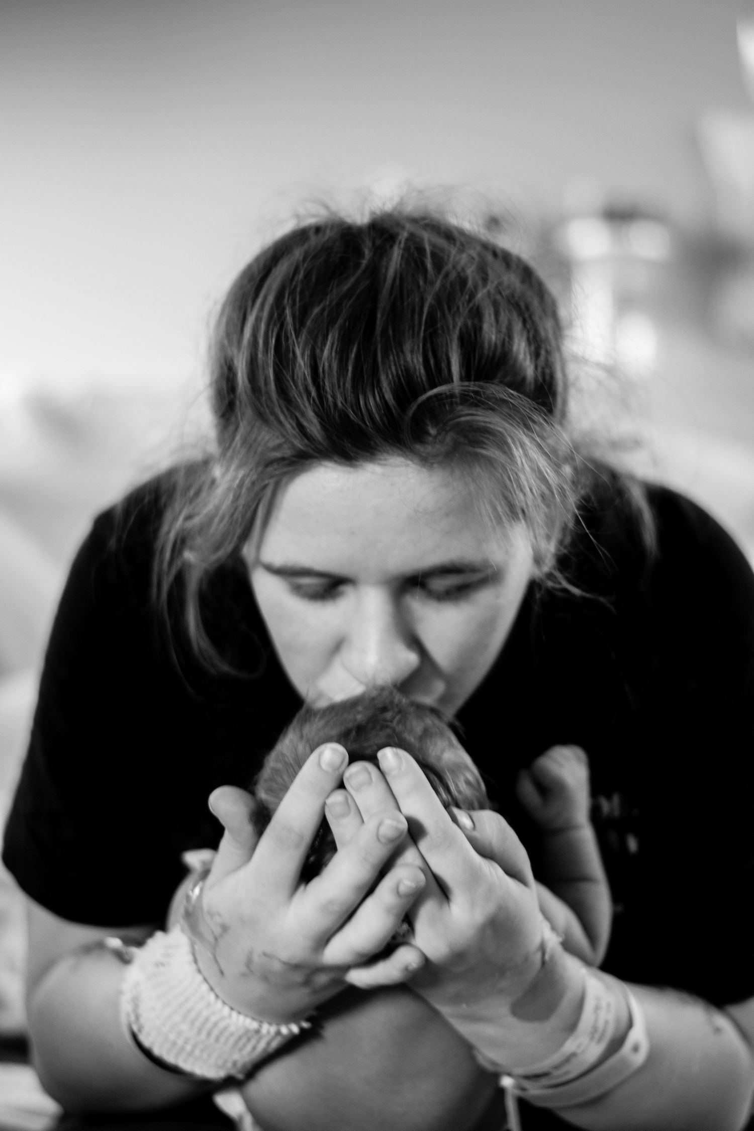 Black and white photo of a young woman smelling a fresh baked bread roll with both hands.