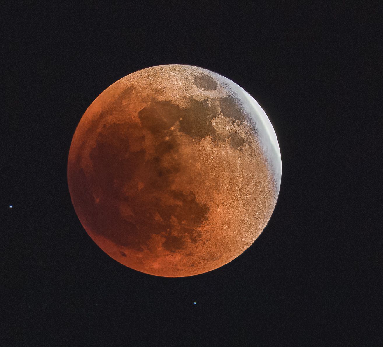 Blood moon lunar eclipse glowing deep red-orange against a dark night sky.