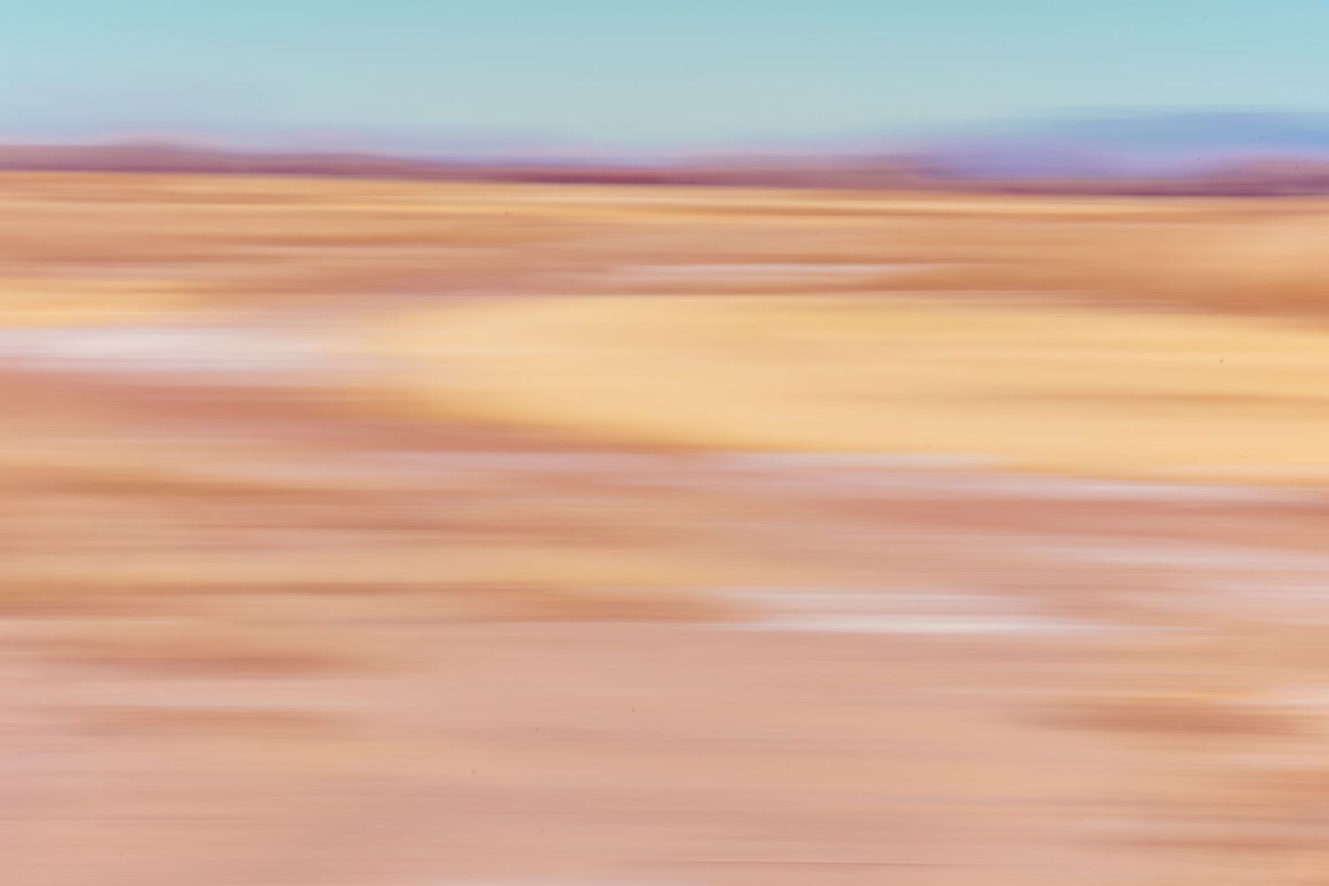 Abstract motion blur photograph of a desert landscape in warm sandy pink and orange tones.
