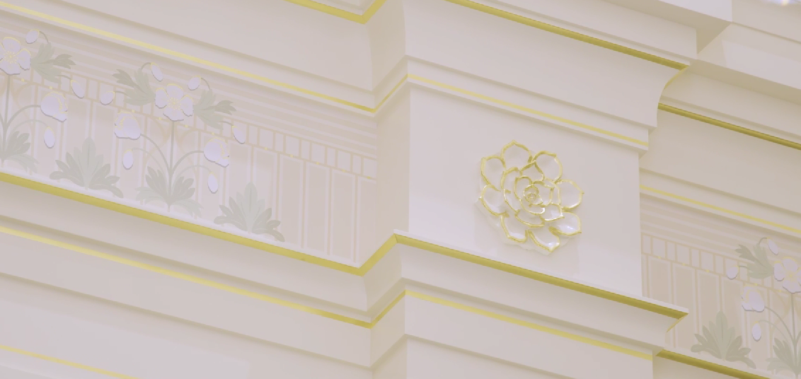 Elegant white architectural molding with floral relief details and subtle green accents on a classical building facade.