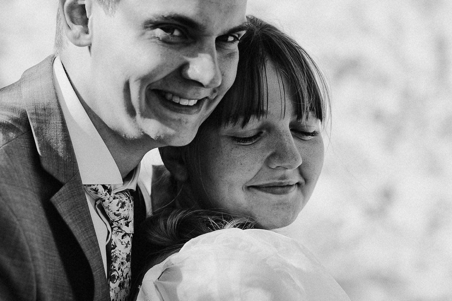 Black and white close-up of a happy couple sharing a candid moment on their wedding day.