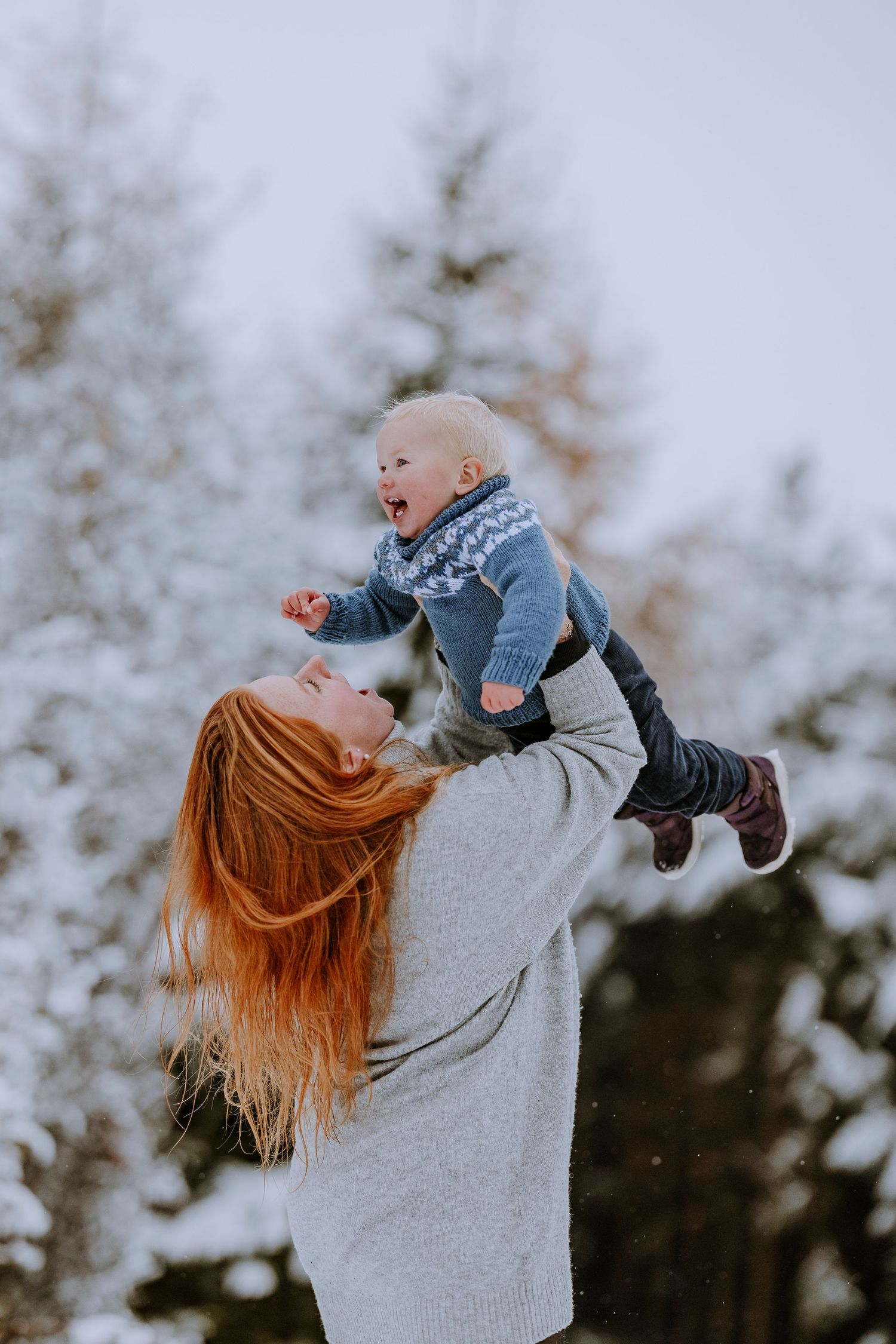 Playful winter moment with child being lifted high in snow-covered setting.