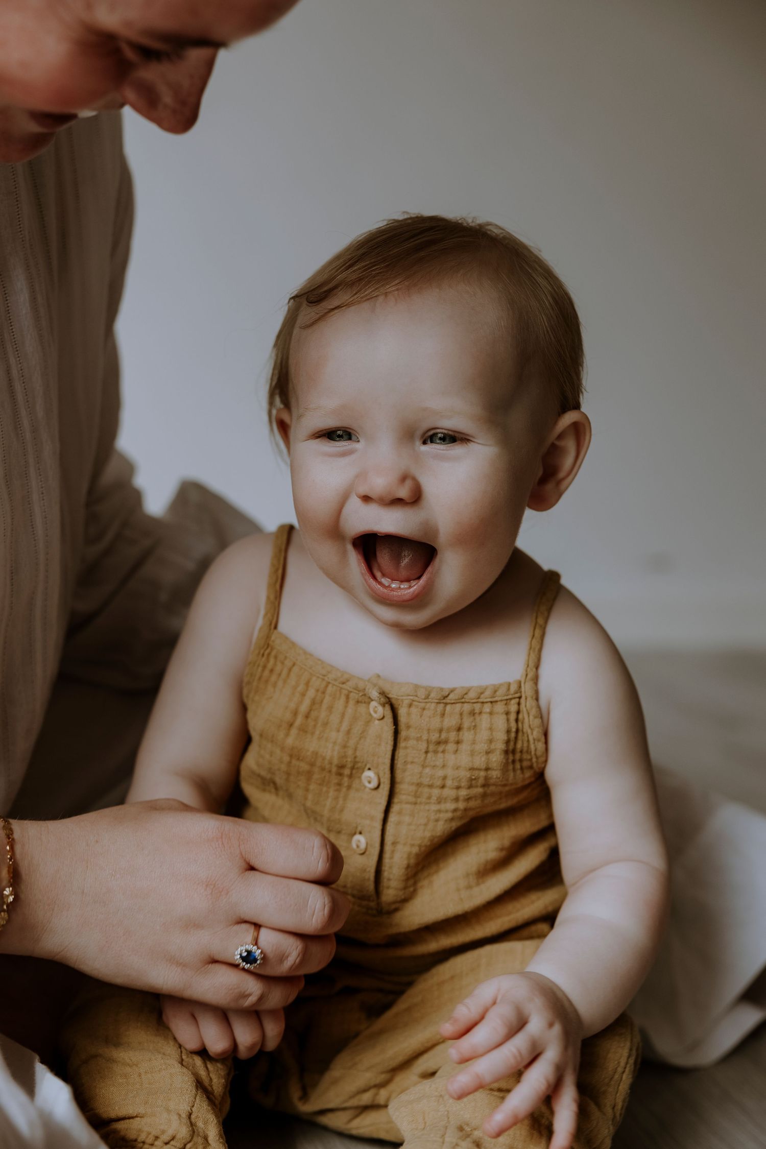 A joyful expression captured in a mustard yellow romper against a neutral background.