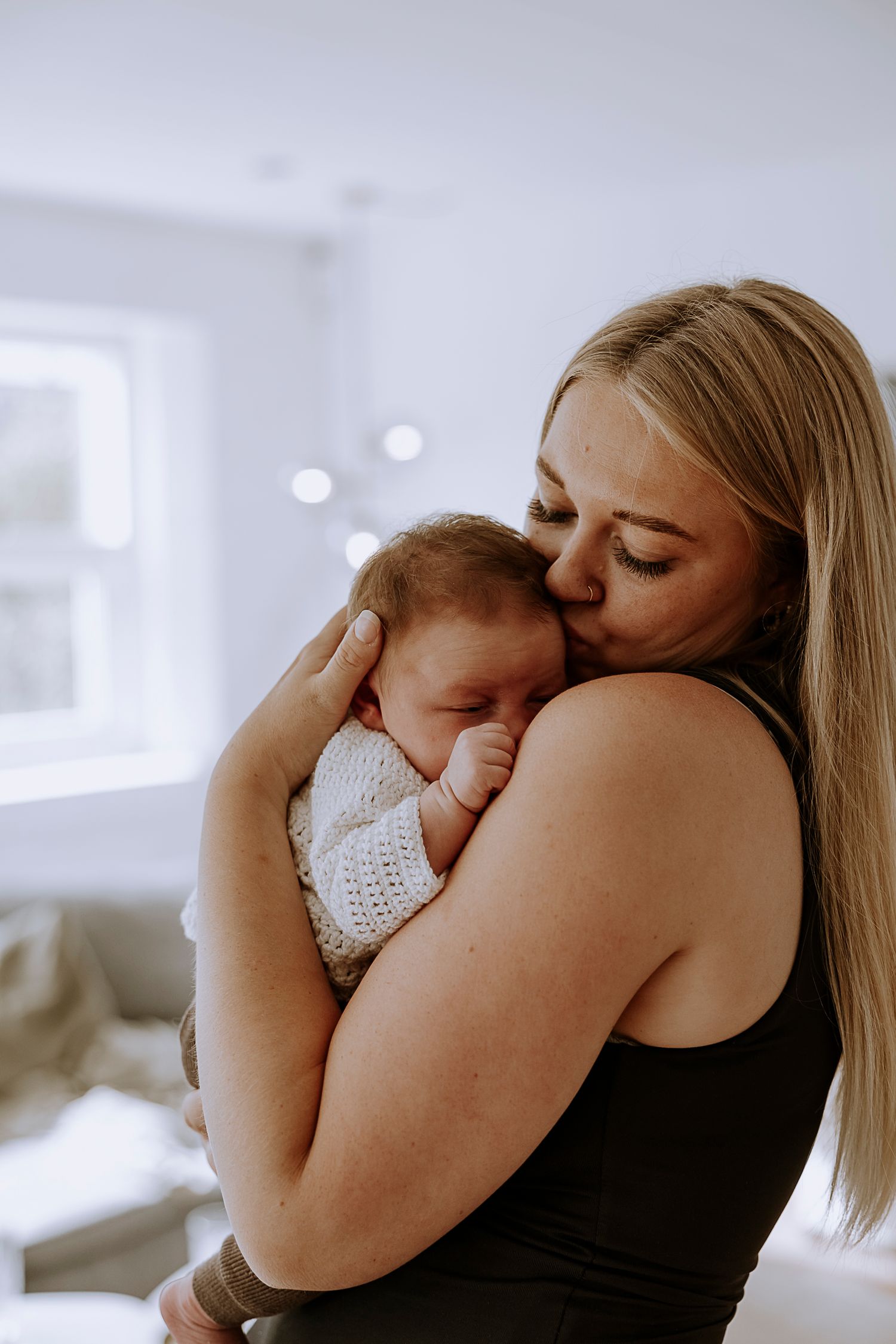 Intimate moment between parent and newborn baby in soft indoor lighting.