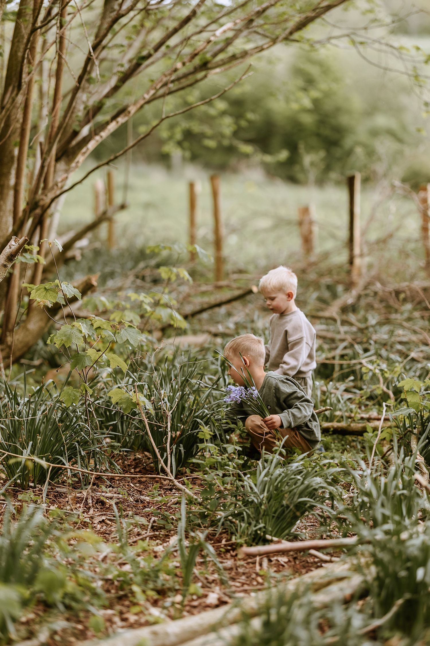 Two children exploring garden path surrounded by trees and greenery.