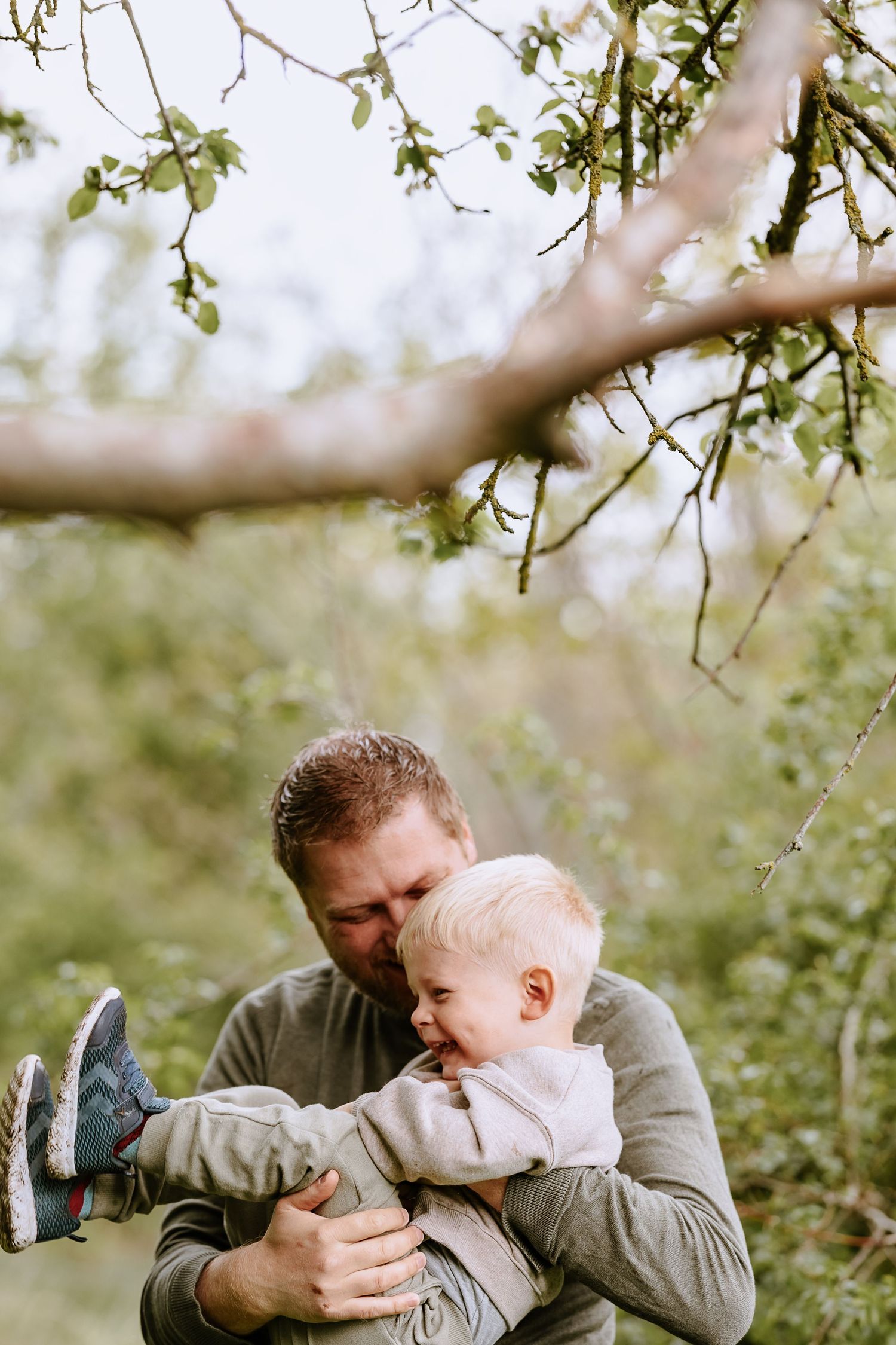 Heartwarming moment shared between parent and toddler underneath blooming spring tree branches.