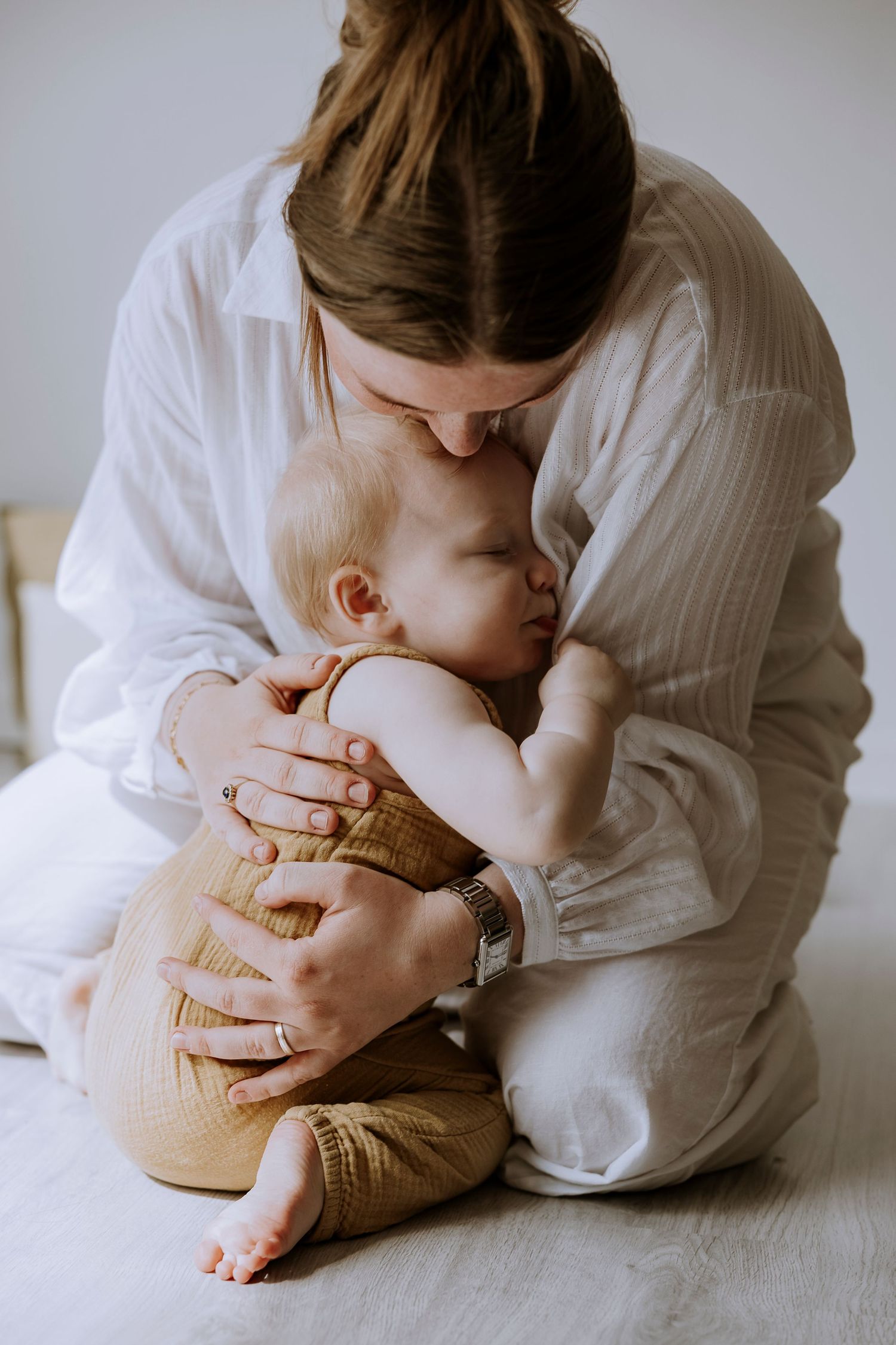 An intimate nurturing moment showcasing gentle care in soft white surroundings.