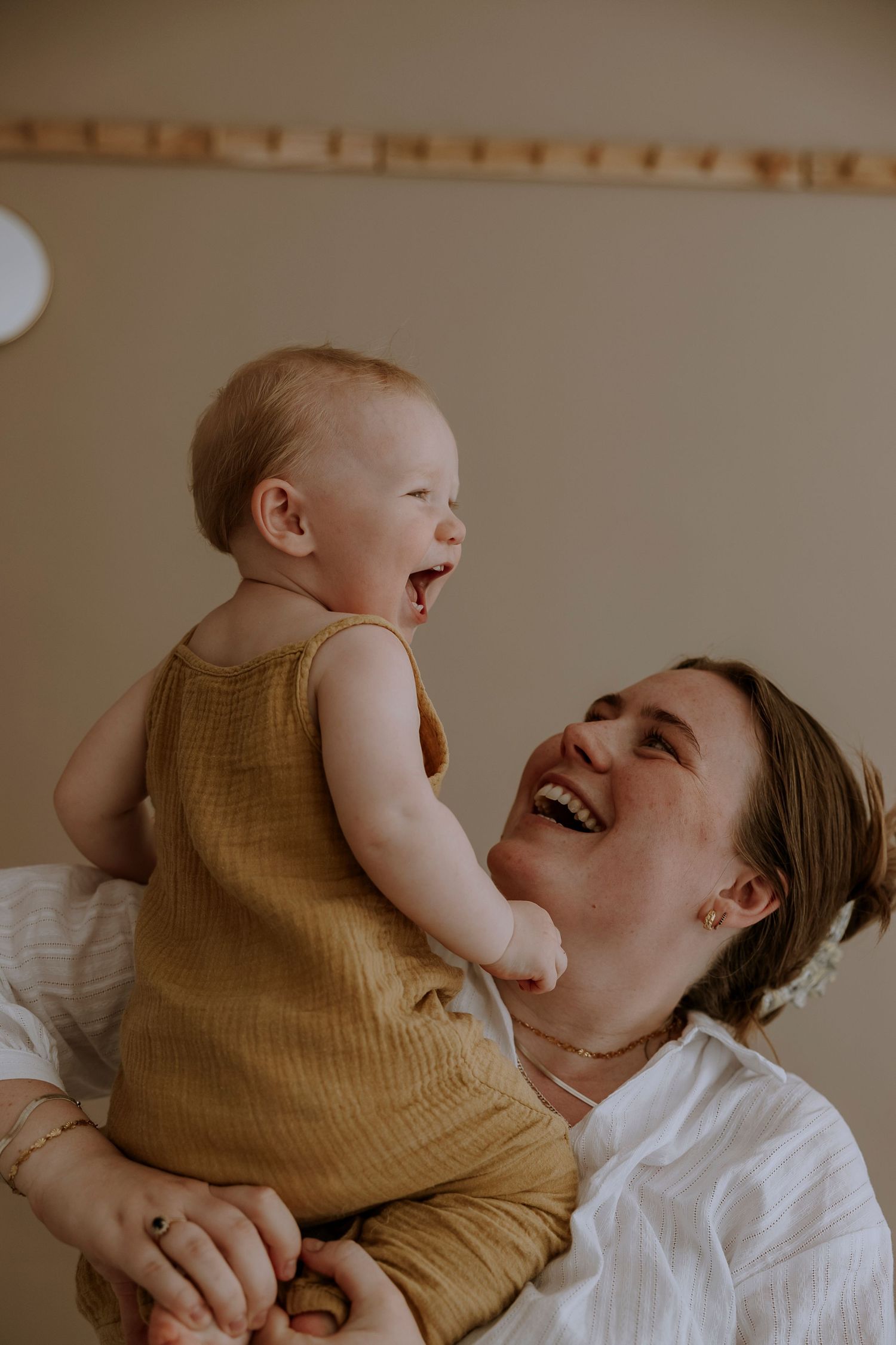 Joyful laughter shared between parent in white shirt and baby in yellow romper.