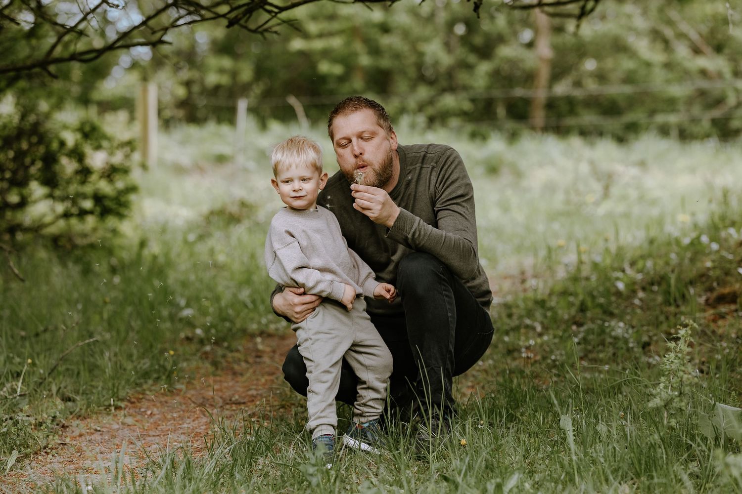 An intimate outdoor moment captured between two people against a natural wooded backdrop.