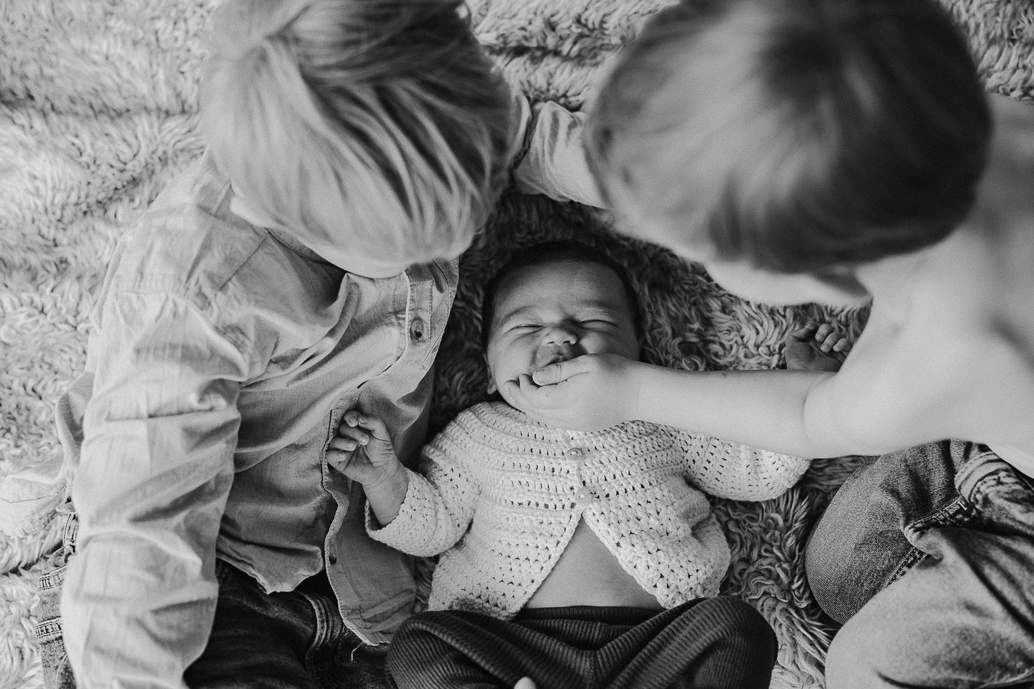 A black and white photograph of children playing together on the ground.