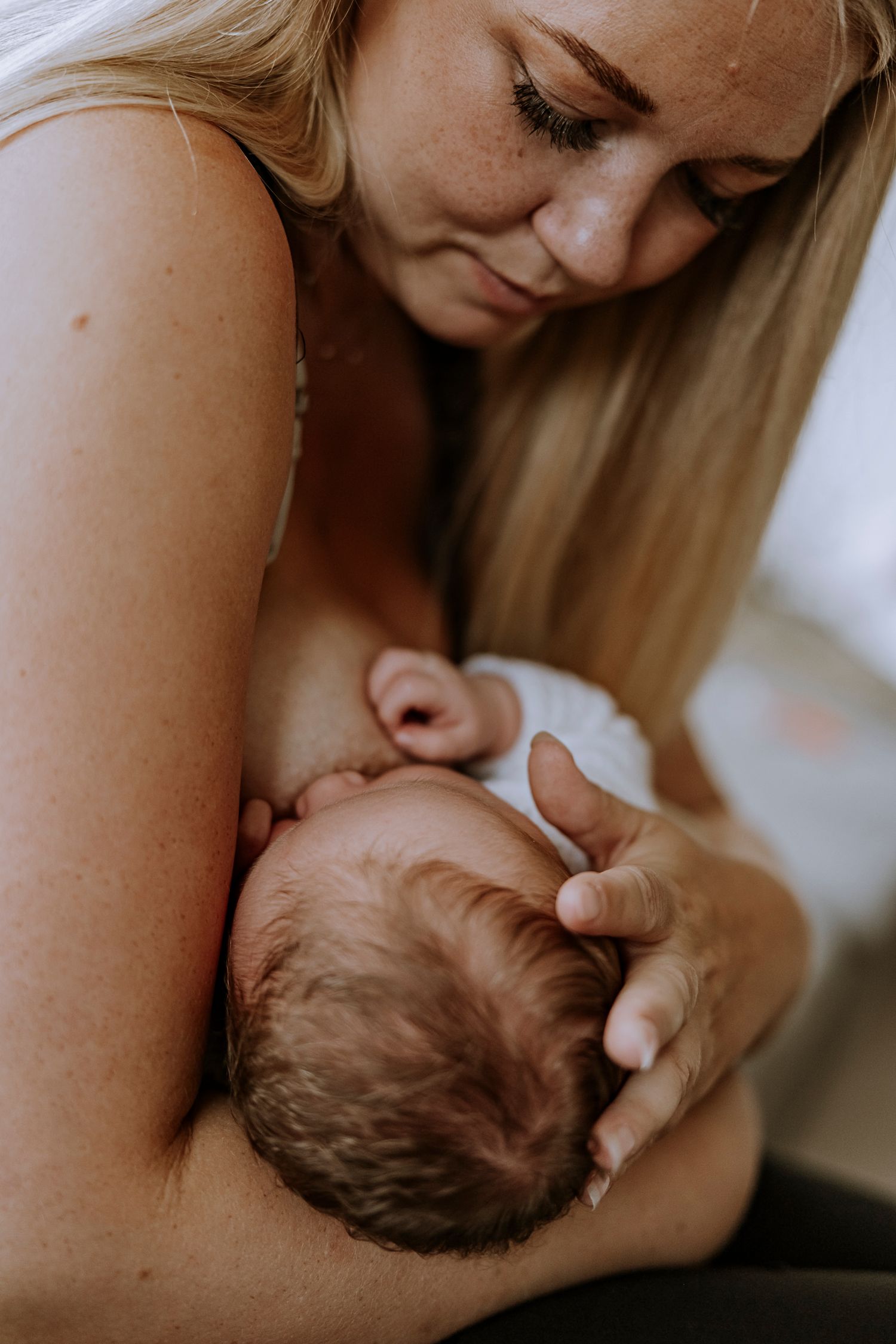 Intimate close-up portrait of nurturing moment with sleeping newborn.