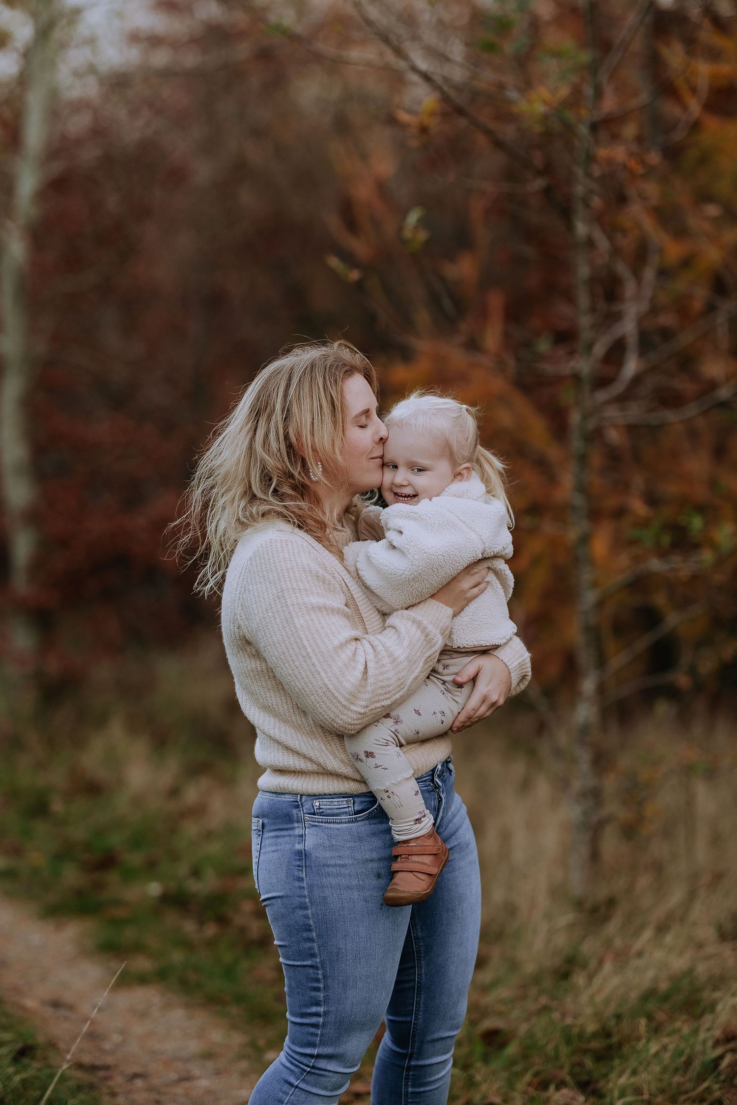 A tender moment between parent and child on an autumn path surrounded by warm fall foliage.