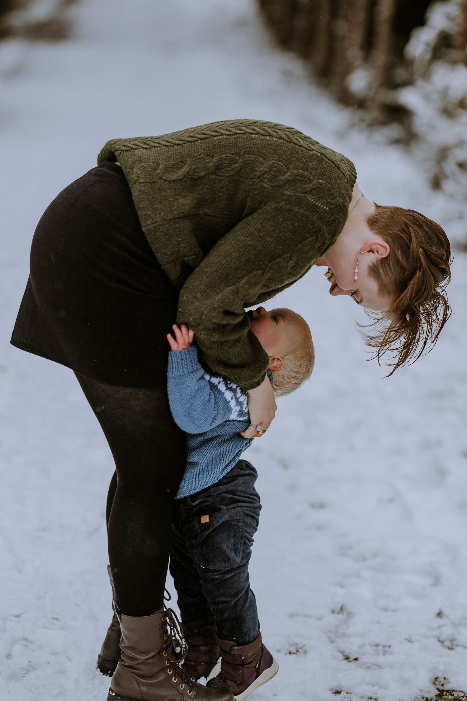 Tender moment between parent and child in snowy winter setting.