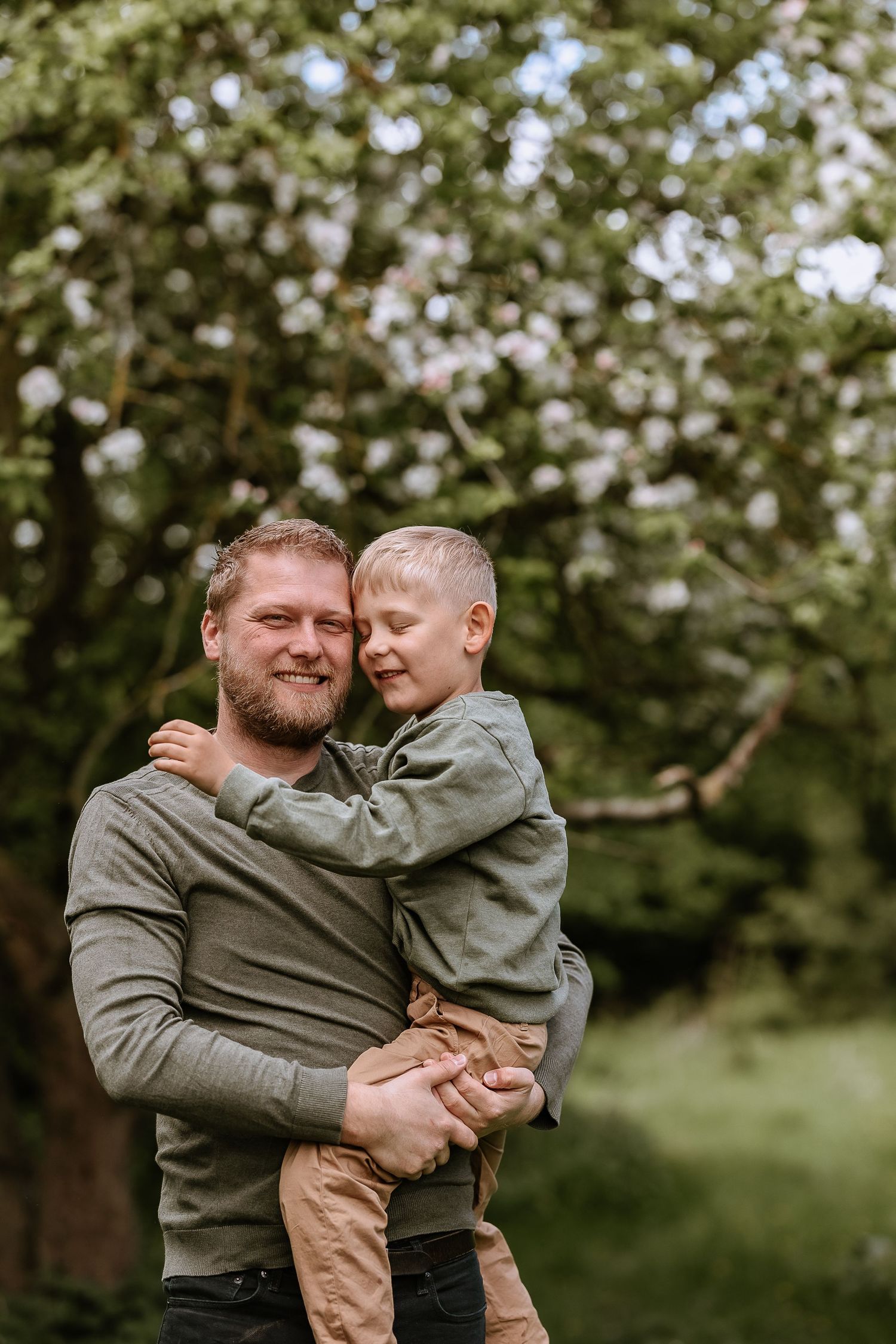A heartwarming outdoor portrait showing loving interaction between parent and child among trees.