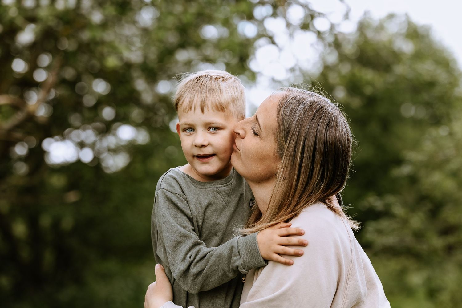 Tender moment between parent and child under spring trees.