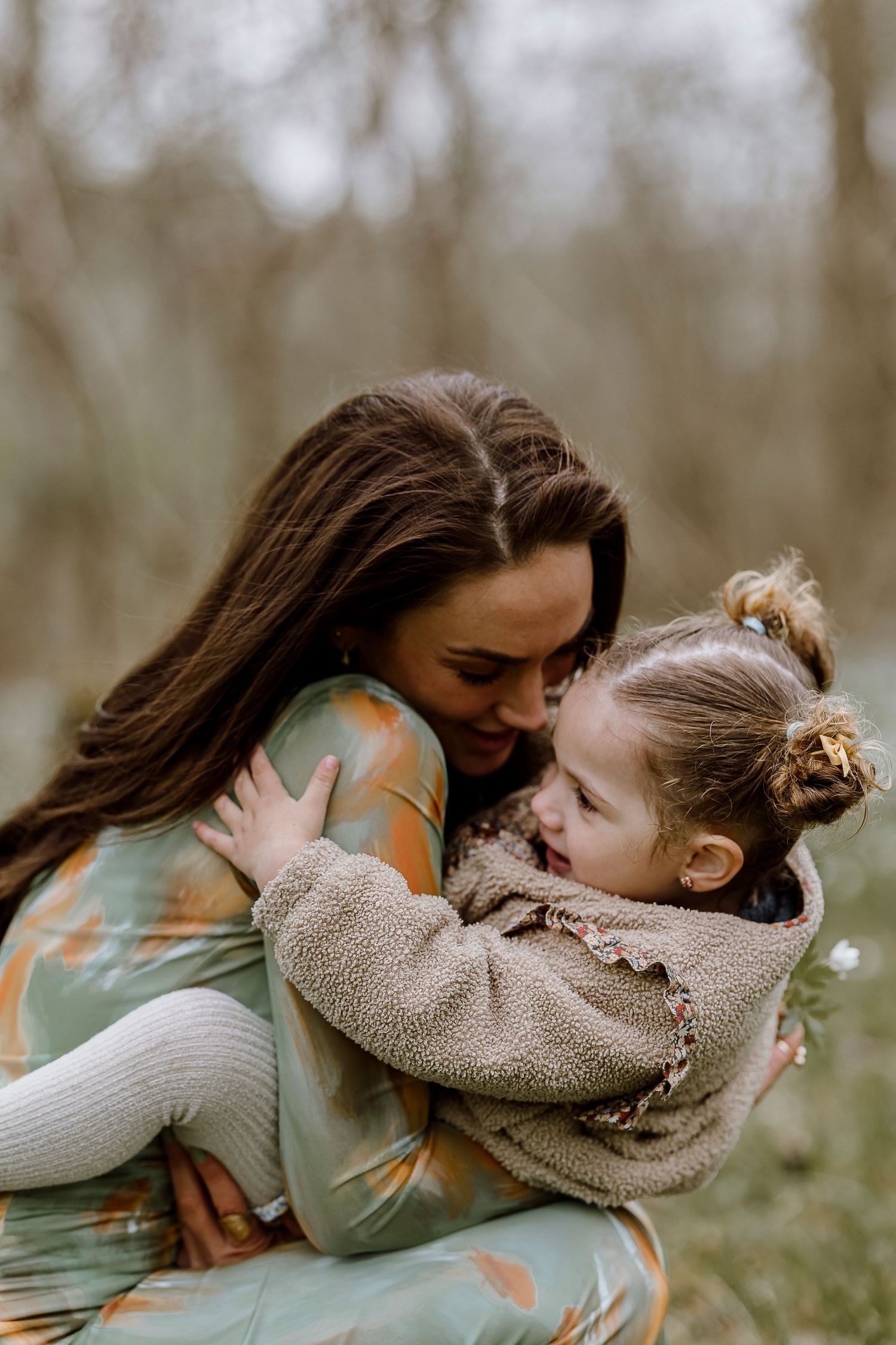 An intimate bonding moment between parent and child in a forest setting.