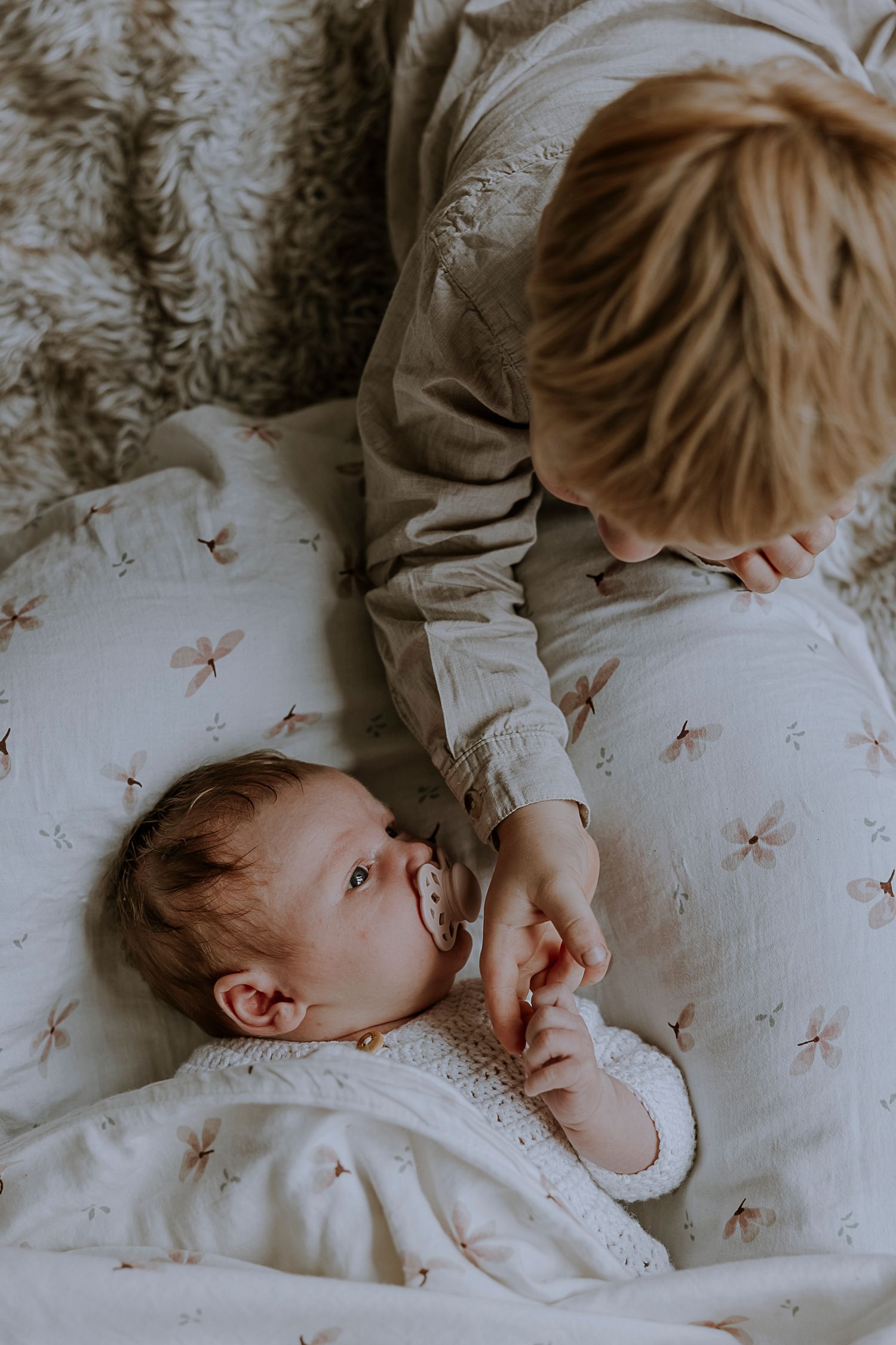 Close-up of siblings interacting on a star-printed white blanket.