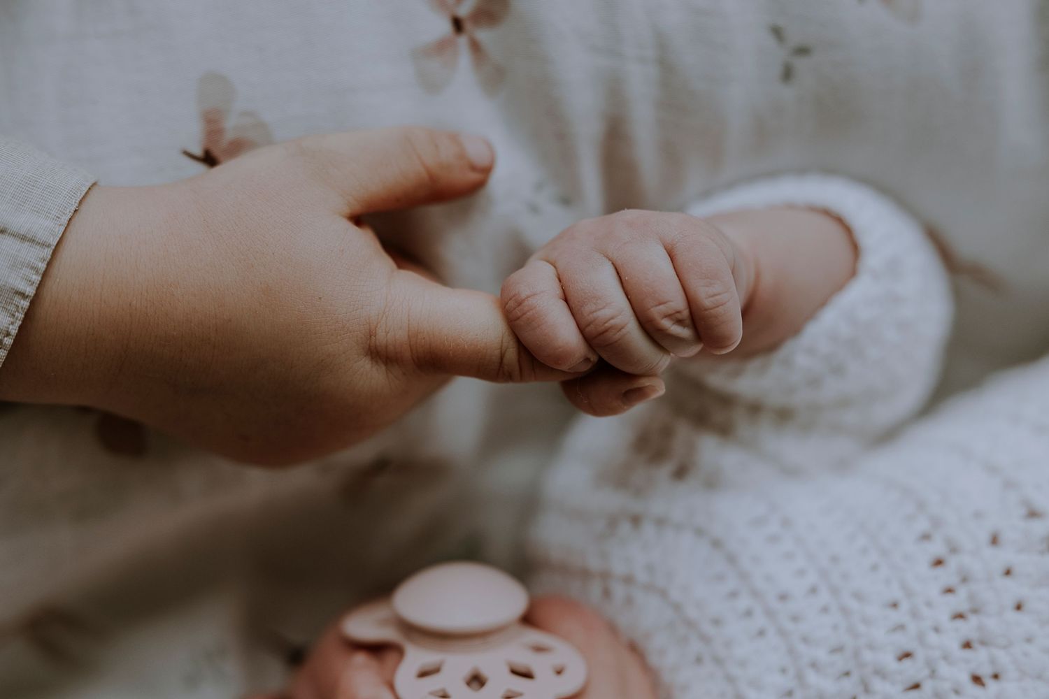 Close-up of tiny baby fingers being held with gentle care.