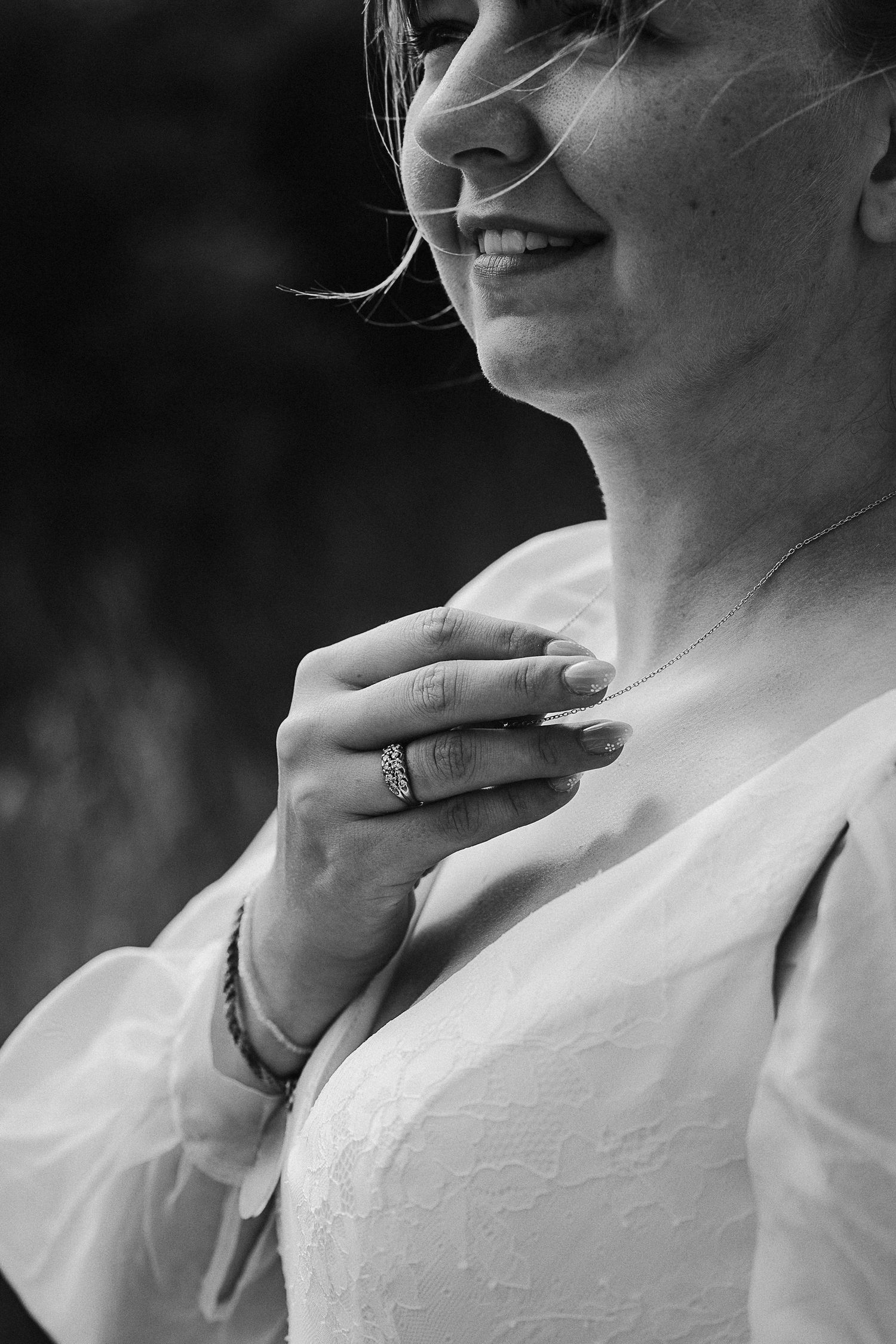Black and white close-up showing wedding ring and gentle smile.