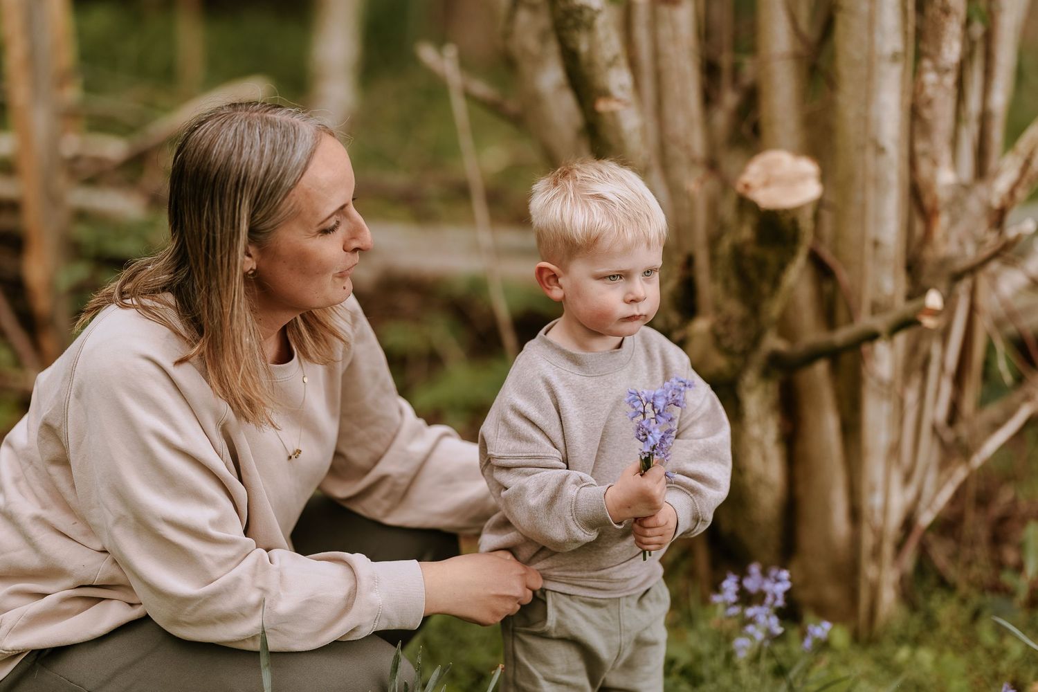 Tender outdoor moment between parent and child examining purple flowers.