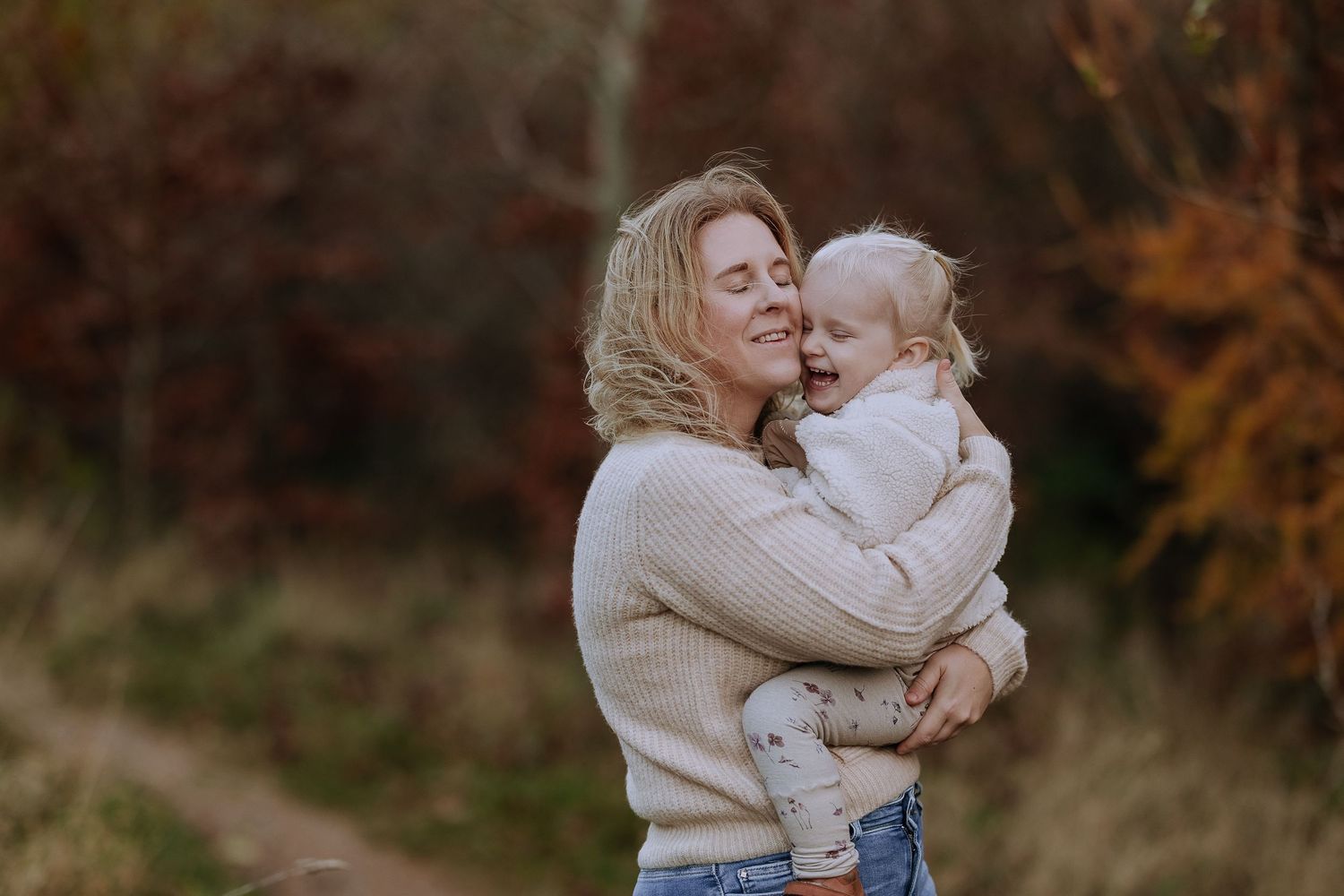 A tender outdoor moment between parent and child in cozy sweaters against an autumn background.