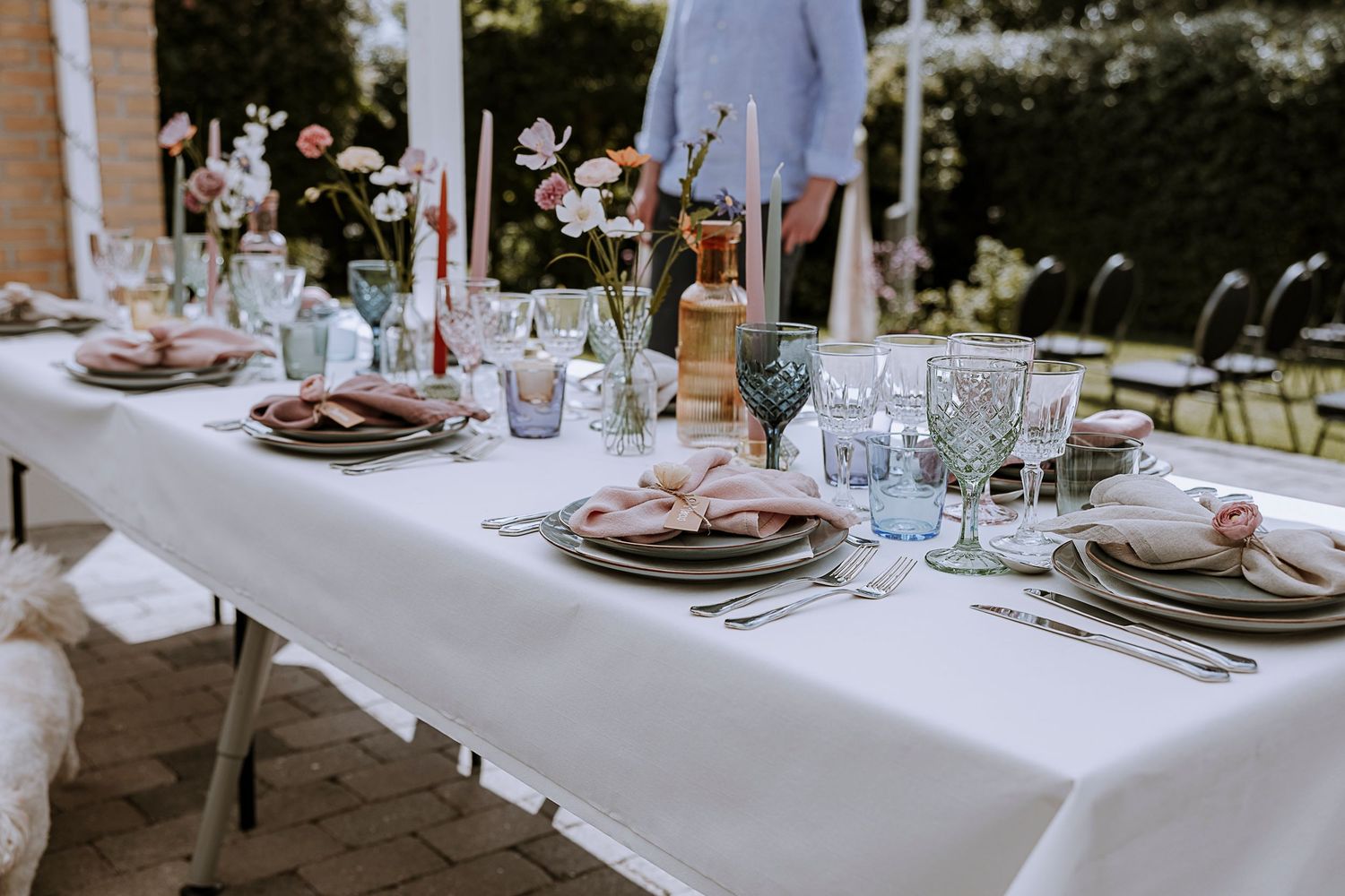 Elegant table setting with white linens, plates and glassware for outdoor wedding reception.