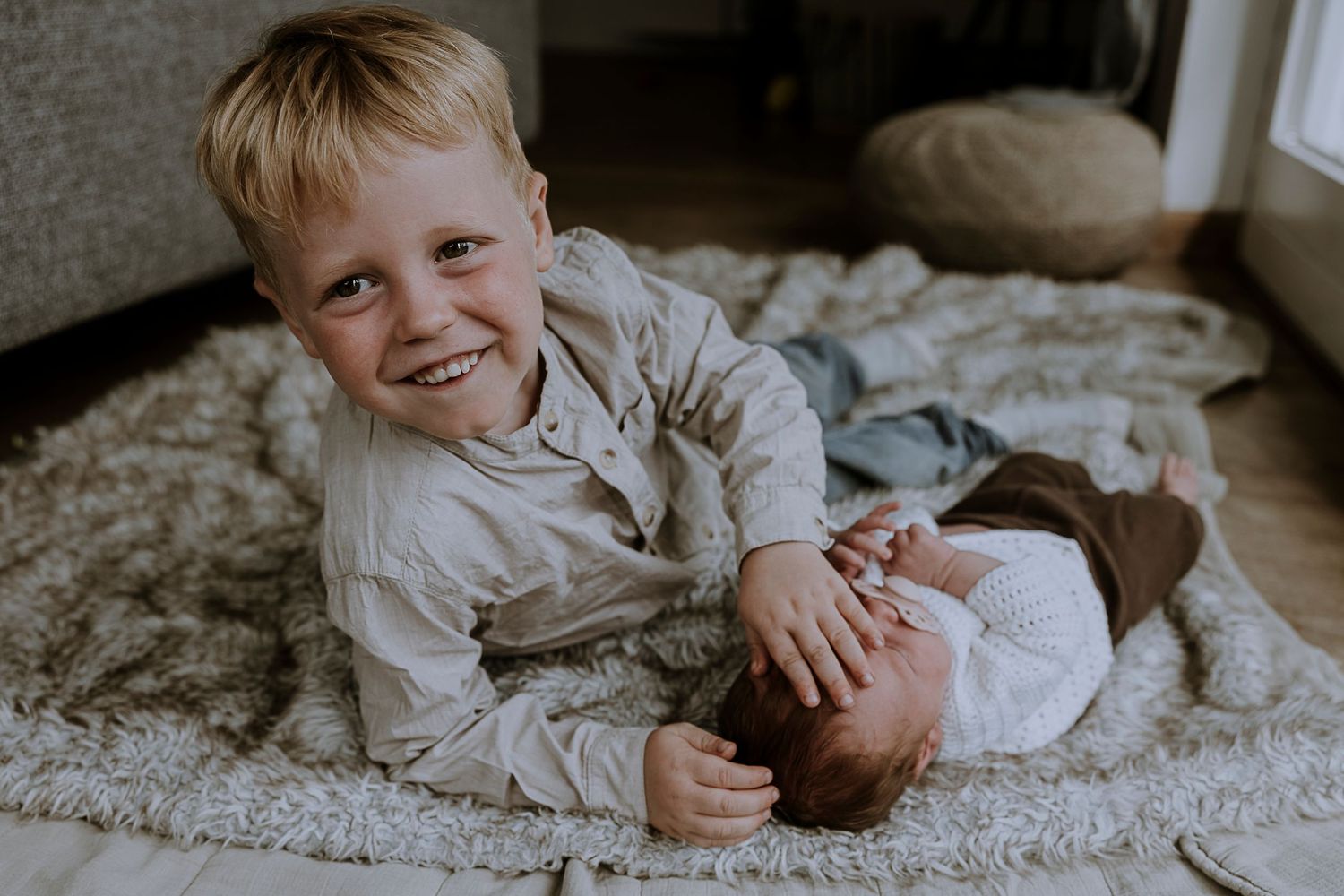 A joyful sibling bonding moment captured on a plush carpet.