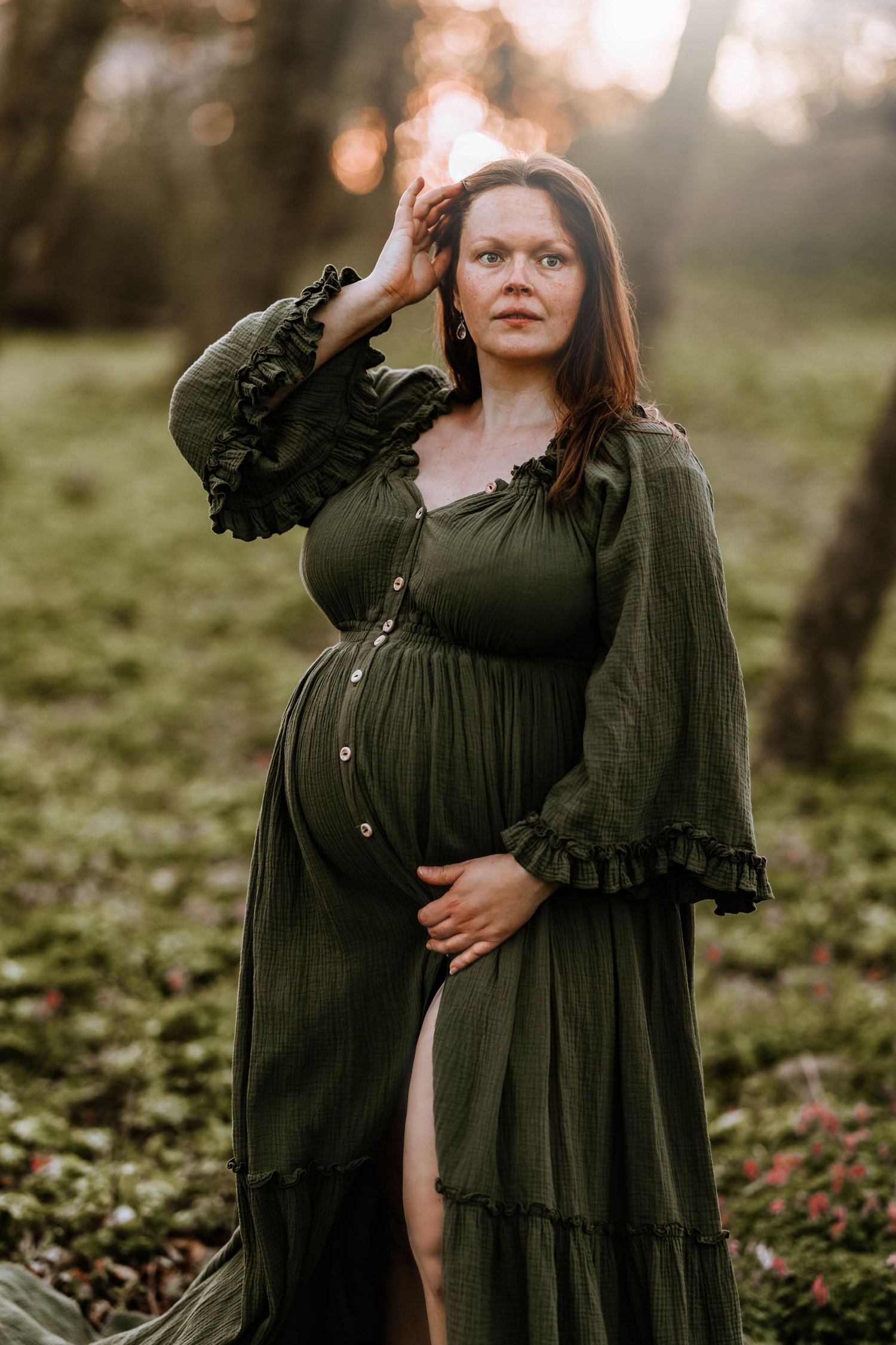 Sunset maternity portrait featuring a dramatic olive green dress with ruffled sleeves.