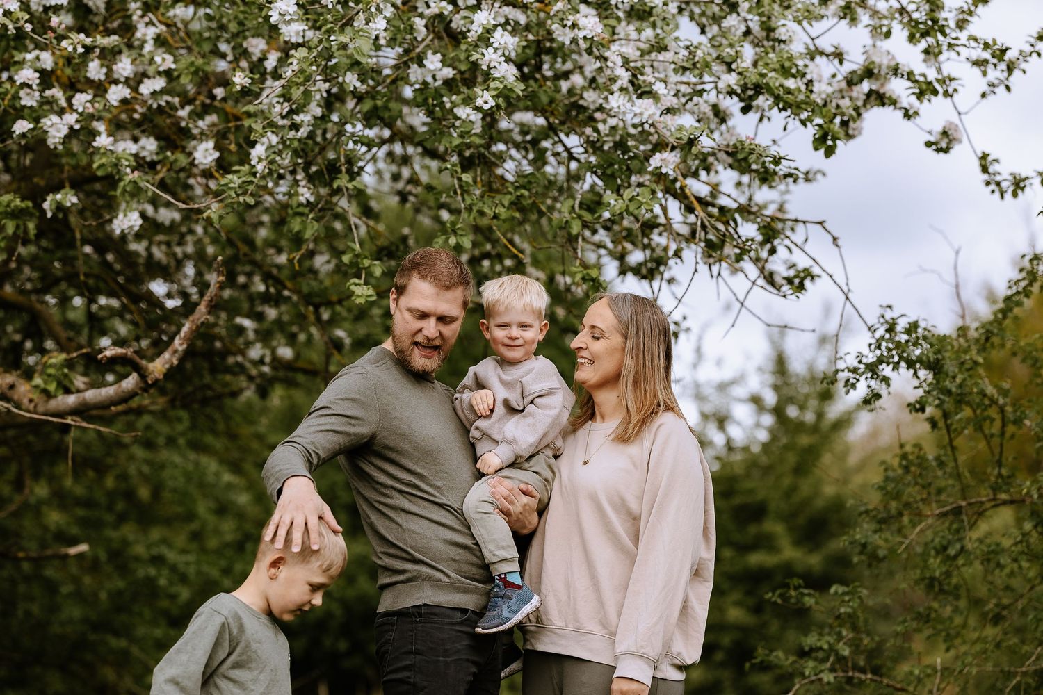 Family portrait outdoors with children under blooming spring tree.