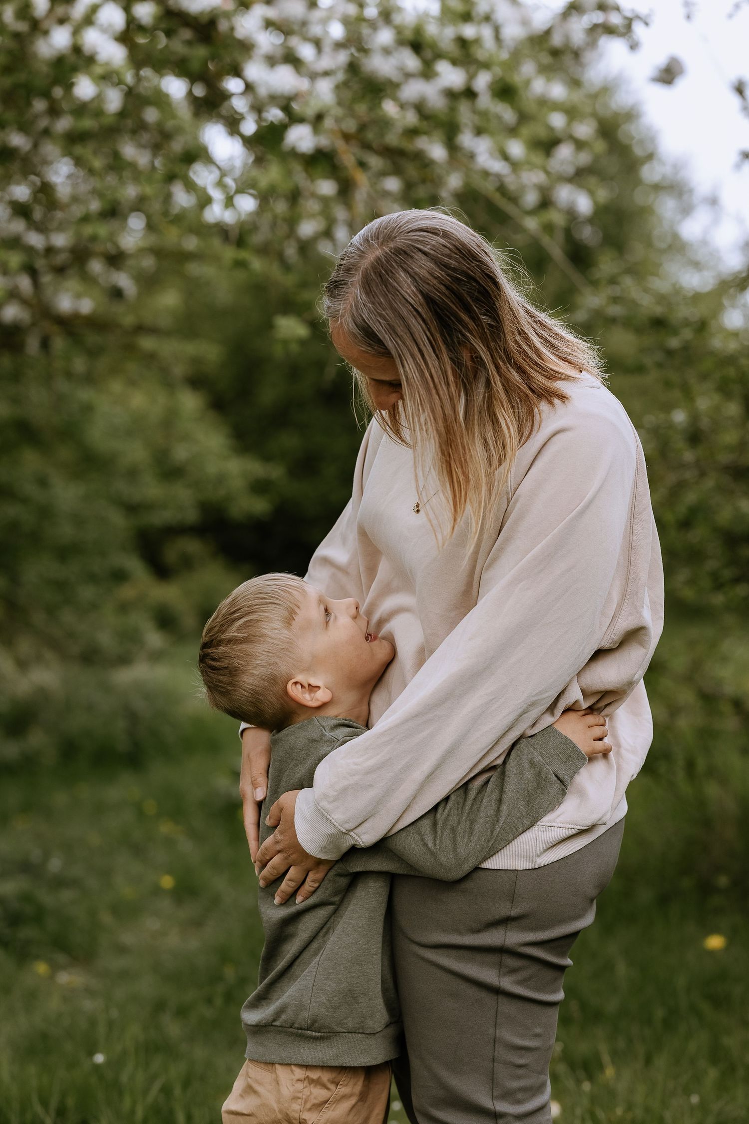 Tender embrace between parent and child outdoors in a lush green garden setting.