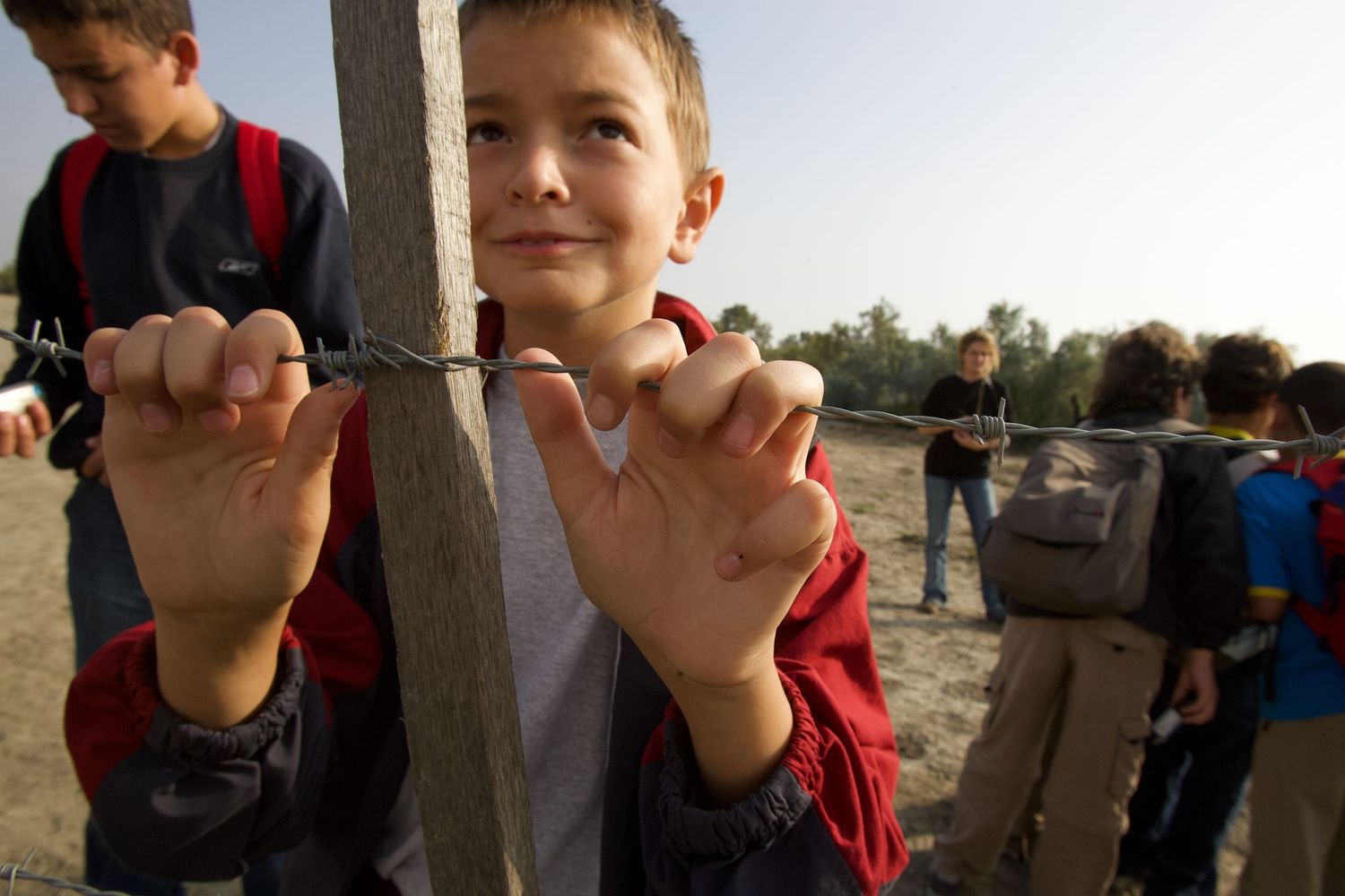 Hands grip a metal pole against a bright outdoor background.