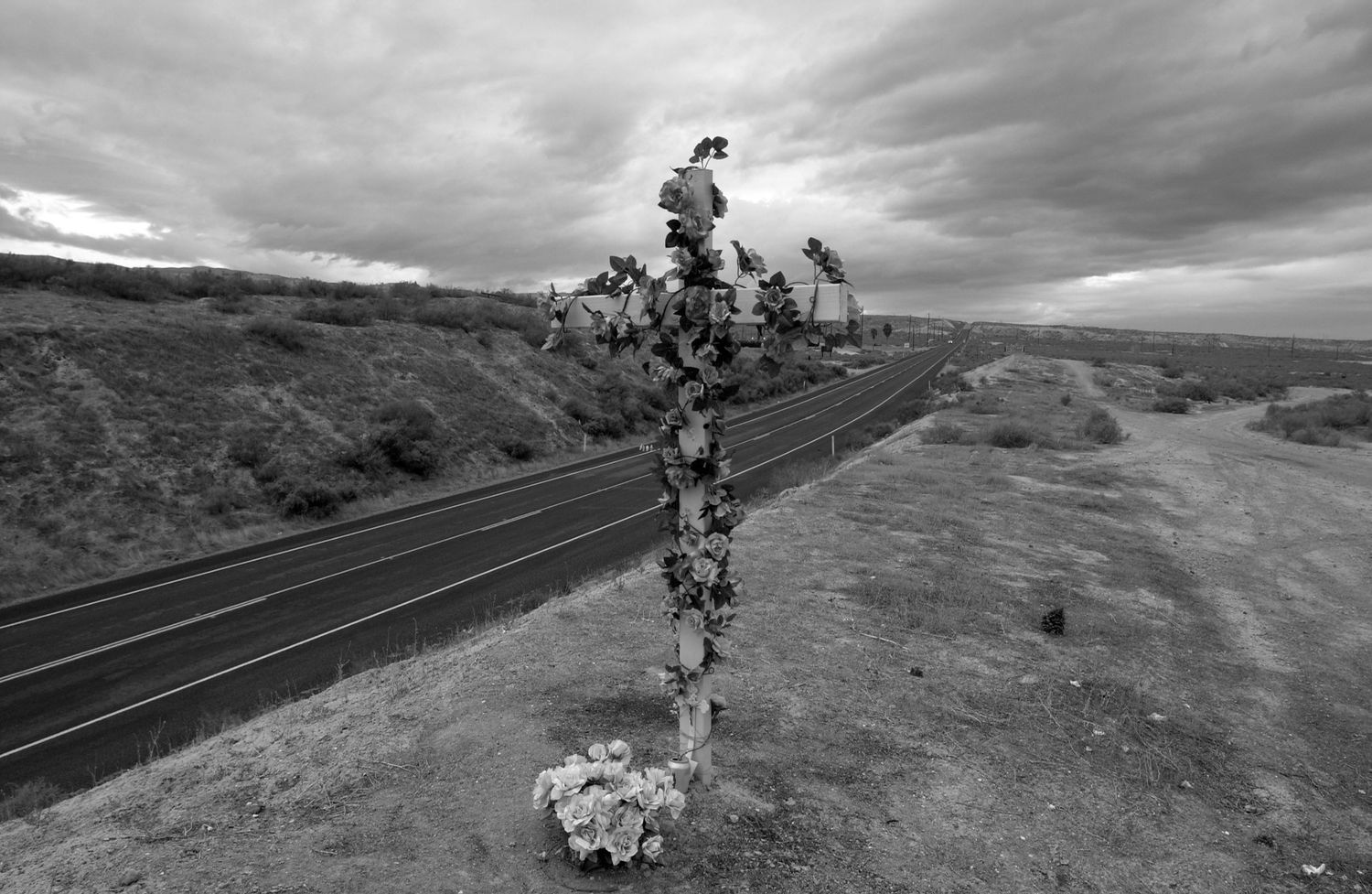 Black and white panoramic series showing cyclists riding along a winding mountain road against dramatic cloudy skies.