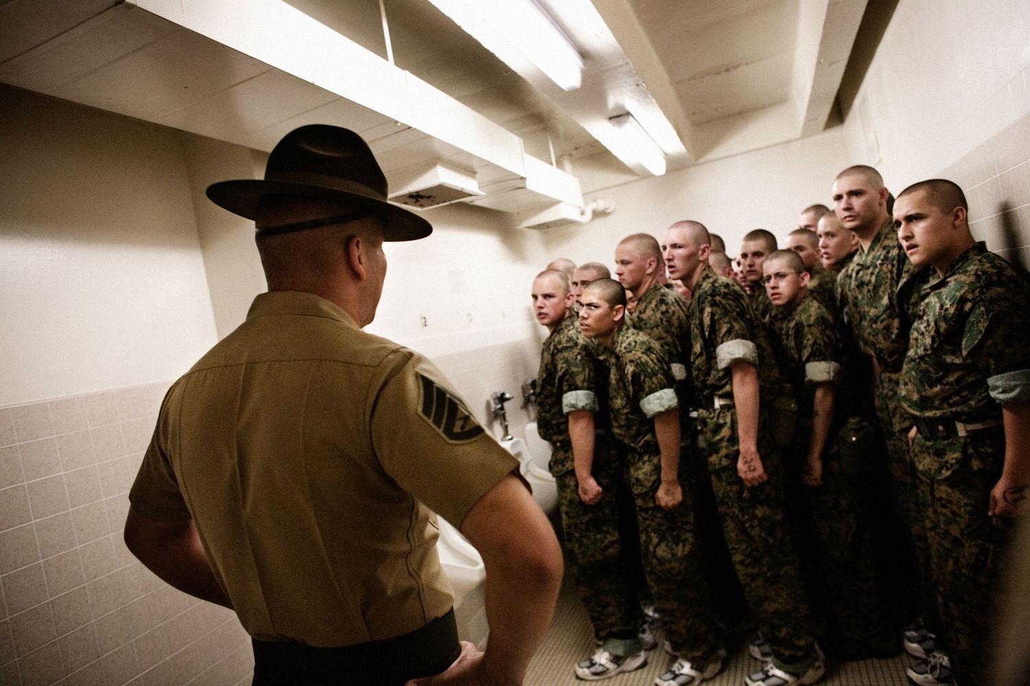 Military training instructors address a group of recruits in a hallway during basic training.