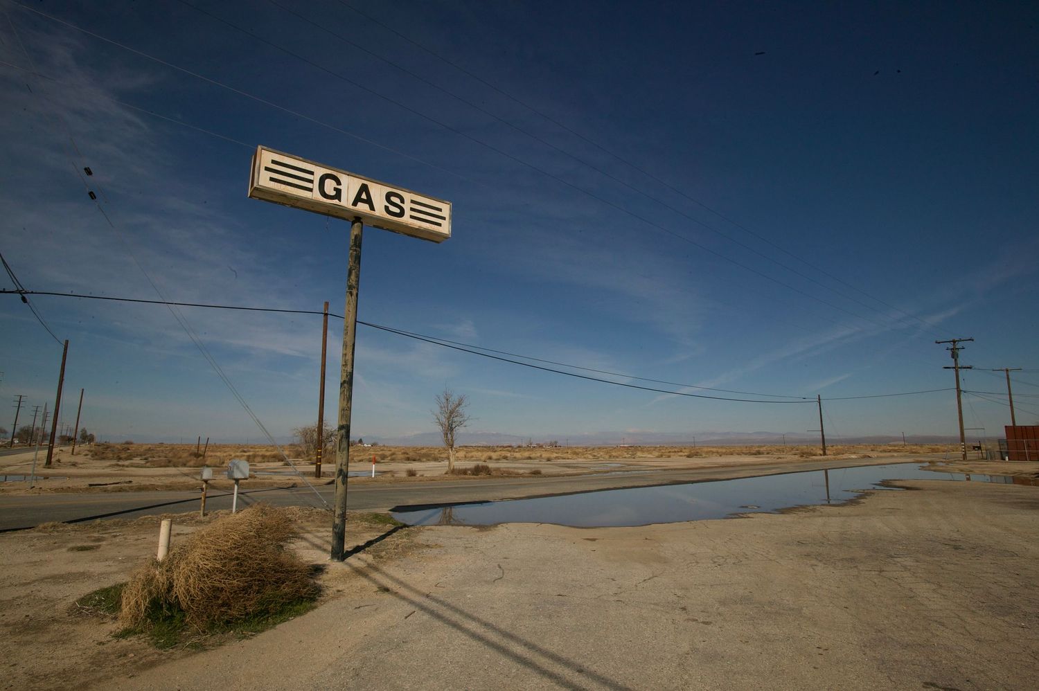 Abandoned gas station sign against desert landscape.