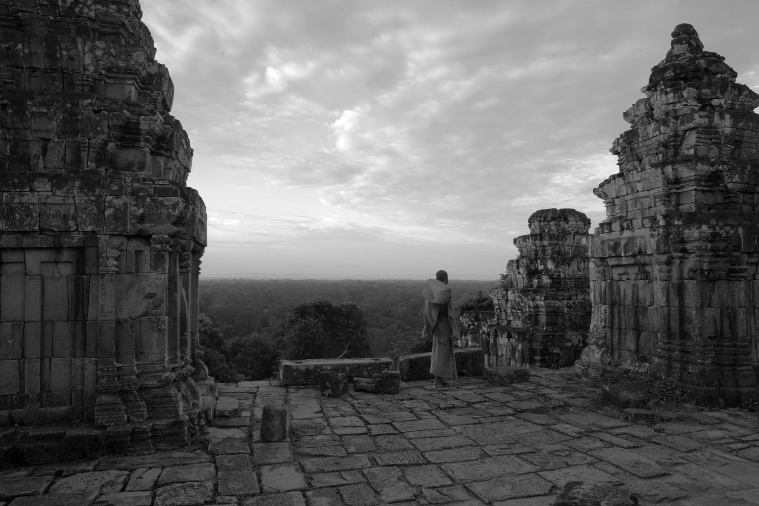 Ancient stone ruins and temple structures photographed at sunset in black and white.