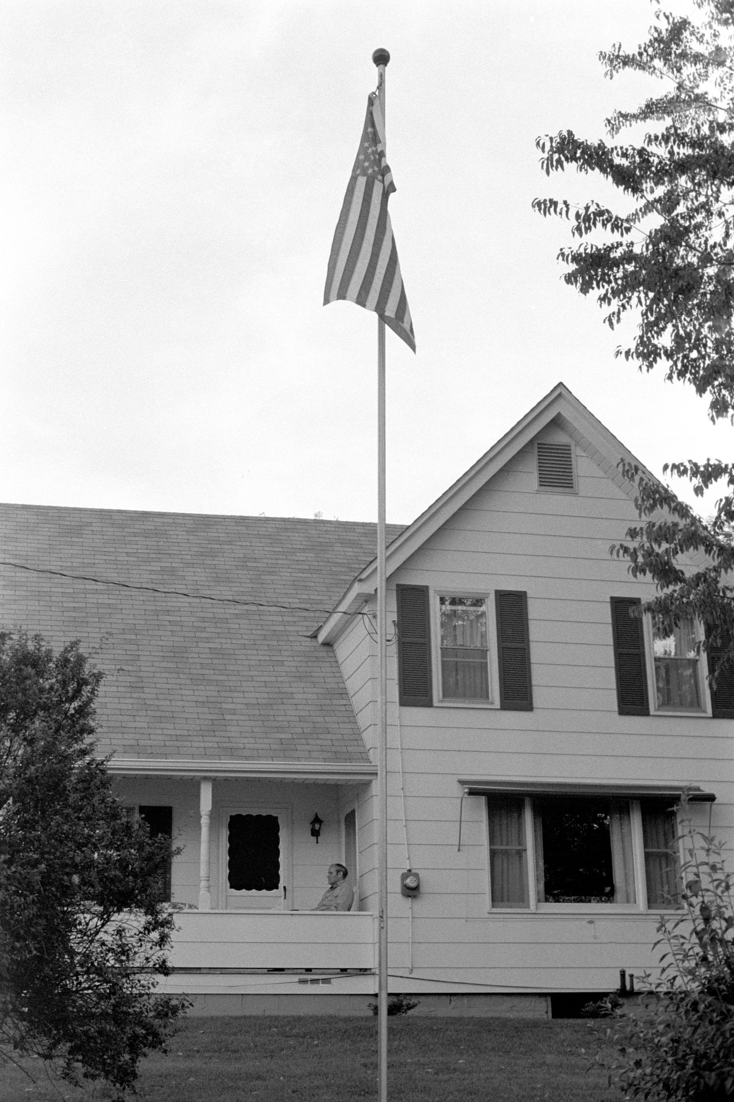 White suburban house with American flag displayed on front facade.