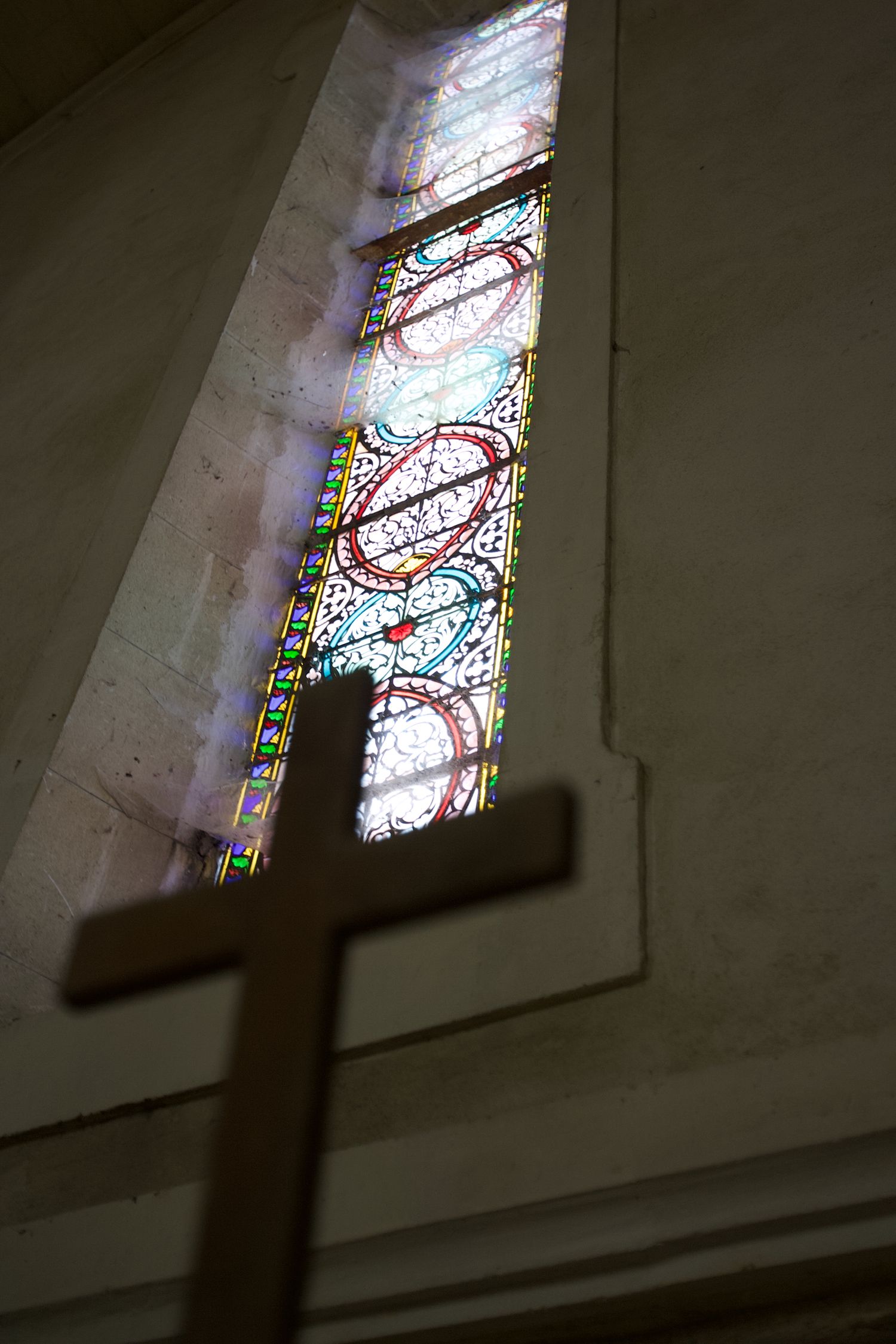 Series of stained glass windows cast colorful light inside a dimly lit church interior.